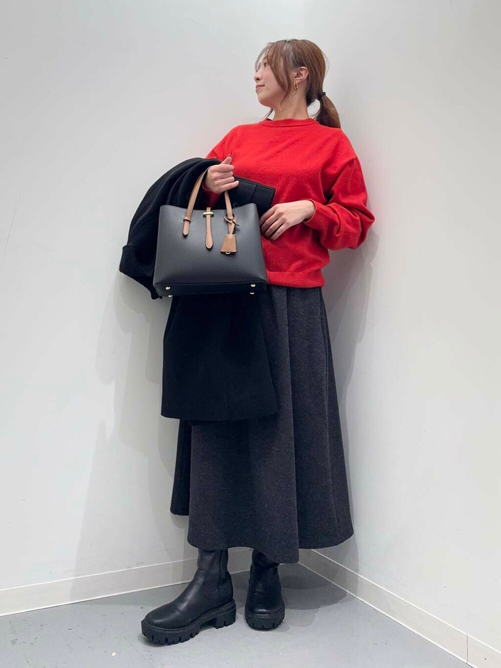 ブラック系のトートバッグ、ブラック系のブーツ、レッド系のニット/セーターを着用したレディースの冬コーディネートの5枚目の写真