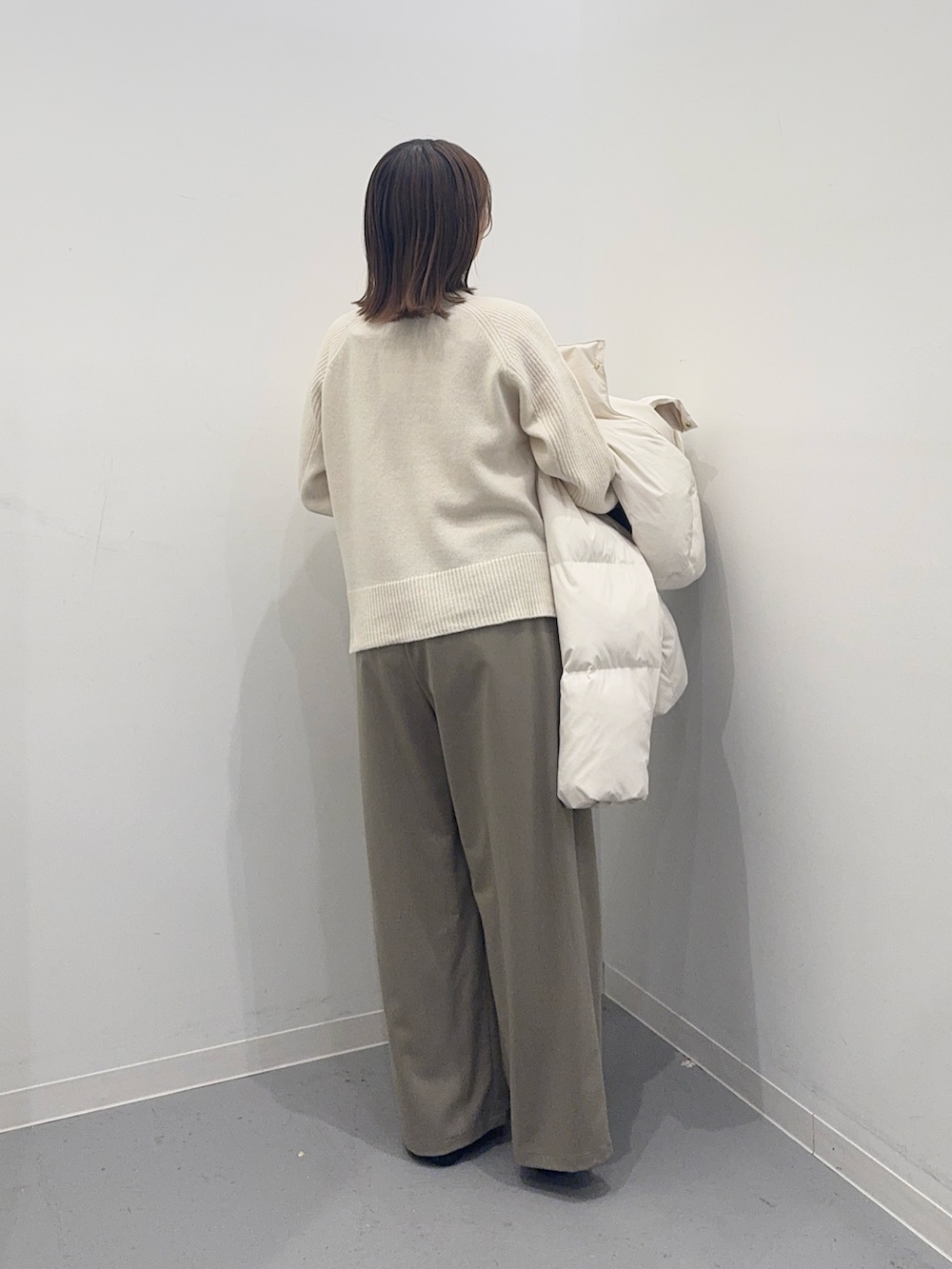 ホワイト系のダウンジャケット/コート、ベージュ系のその他パンツ、ブラック系のハンドバッグを着用したレディースの冬コーディネートの5枚目の写真