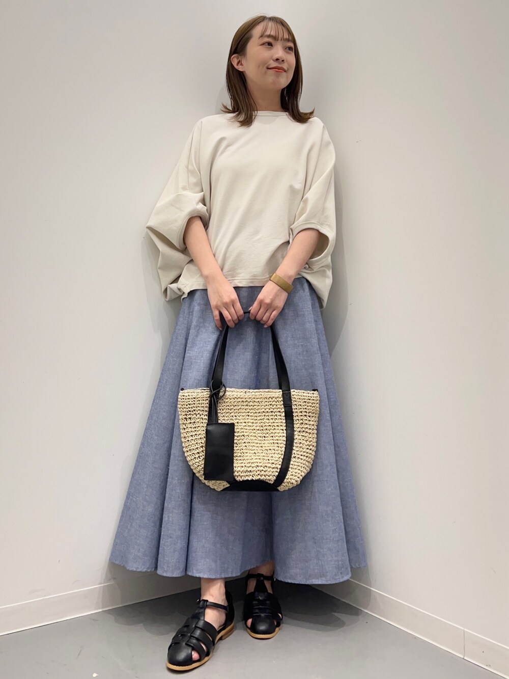 ベージュ系のTシャツ/カットソー、ブルー系のスカート、ブラック系のサンダルを着用したレディースの春コーディネートの4枚目の写真