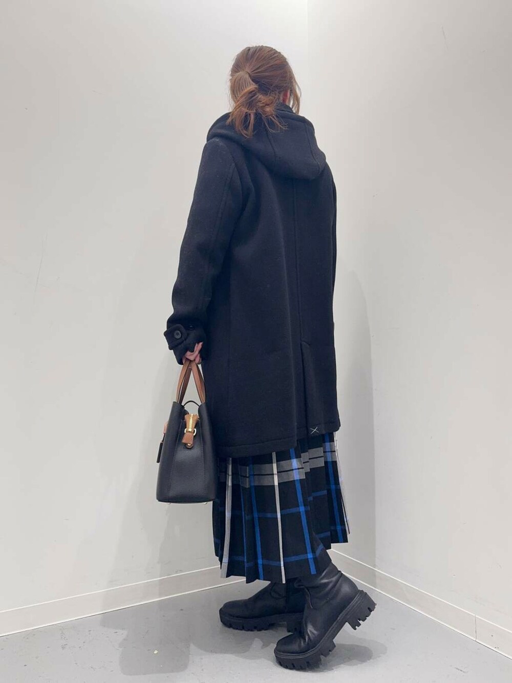 ブラック系のトートバッグ、ブラック系のその他アウター、ブラック系のブーツを着用したレディースの冬コーディネートの7枚目の写真