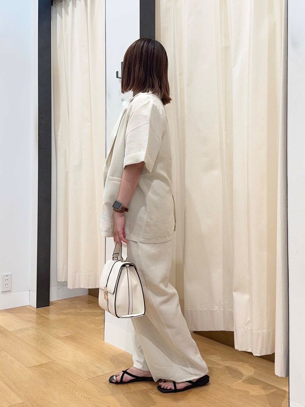 ホワイト系のハンドバッグ、ブラック系のサンダル、ホワイト系のTシャツ/カットソーを着用したレディースの夏コーディネートの3枚目の写真