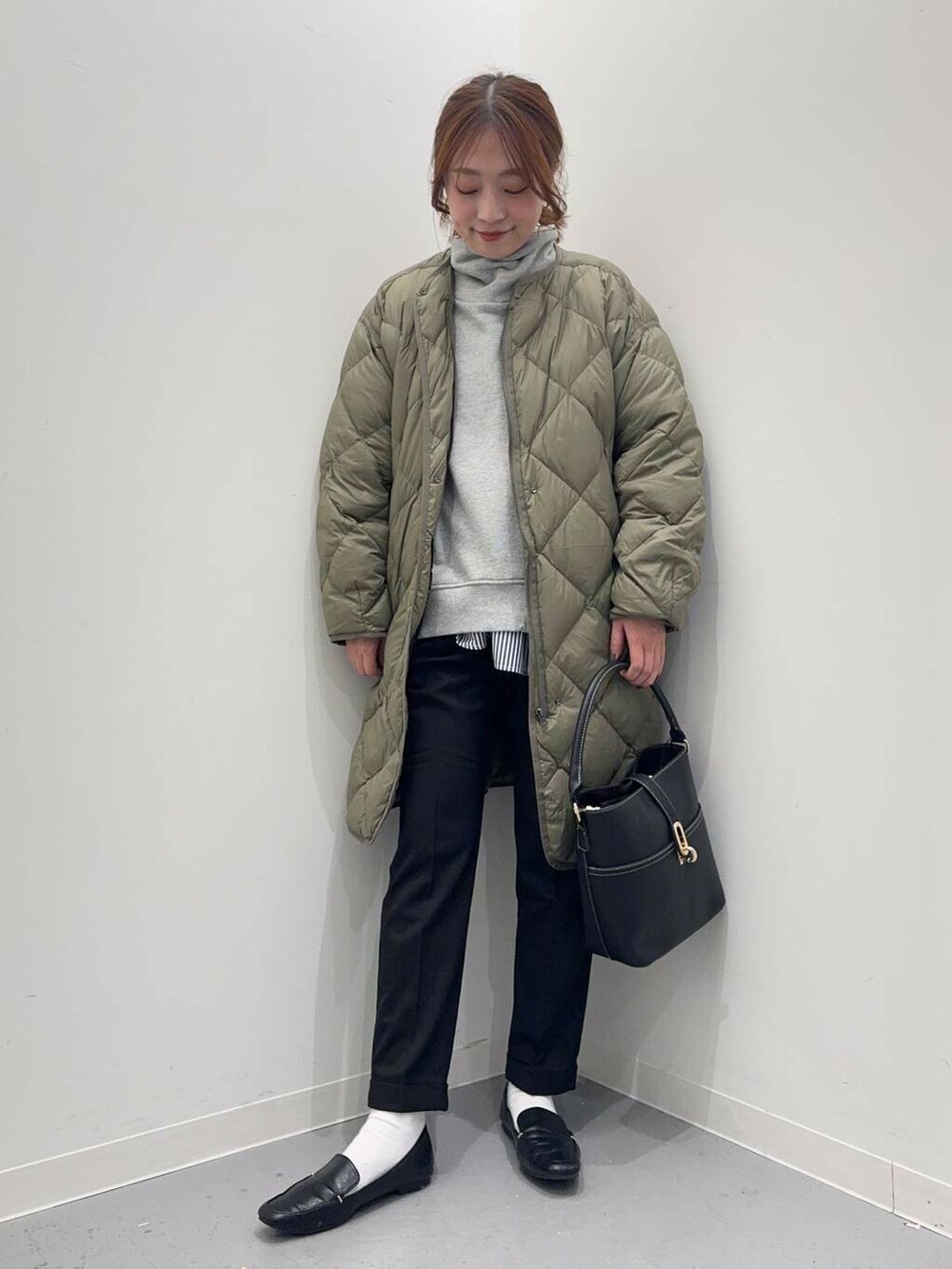 ブラック系のローファー、グリーン系のダウンジャケット/コート、ブルー系のシャツ/ブラウスを着用したレディースの冬コーディネートの2枚目の写真