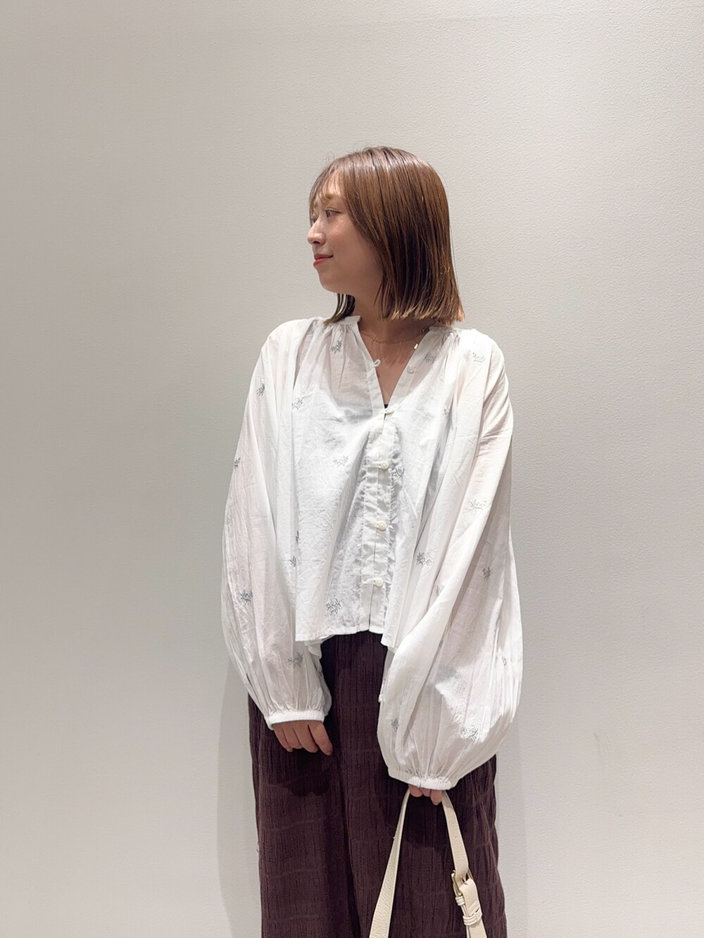 ホワイト系のシャツ/ブラウス、ブラウン系のスカート、ベージュ系のパンプスを着用したレディースの秋コーディネートの6枚目の写真