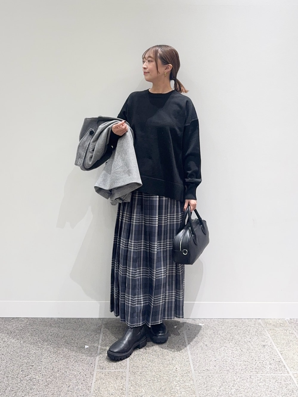 グレー系のその他アウター、ブラック系のニット/セーター、グレー系のスカートを着用したレディースの秋コーディネートの5枚目の写真