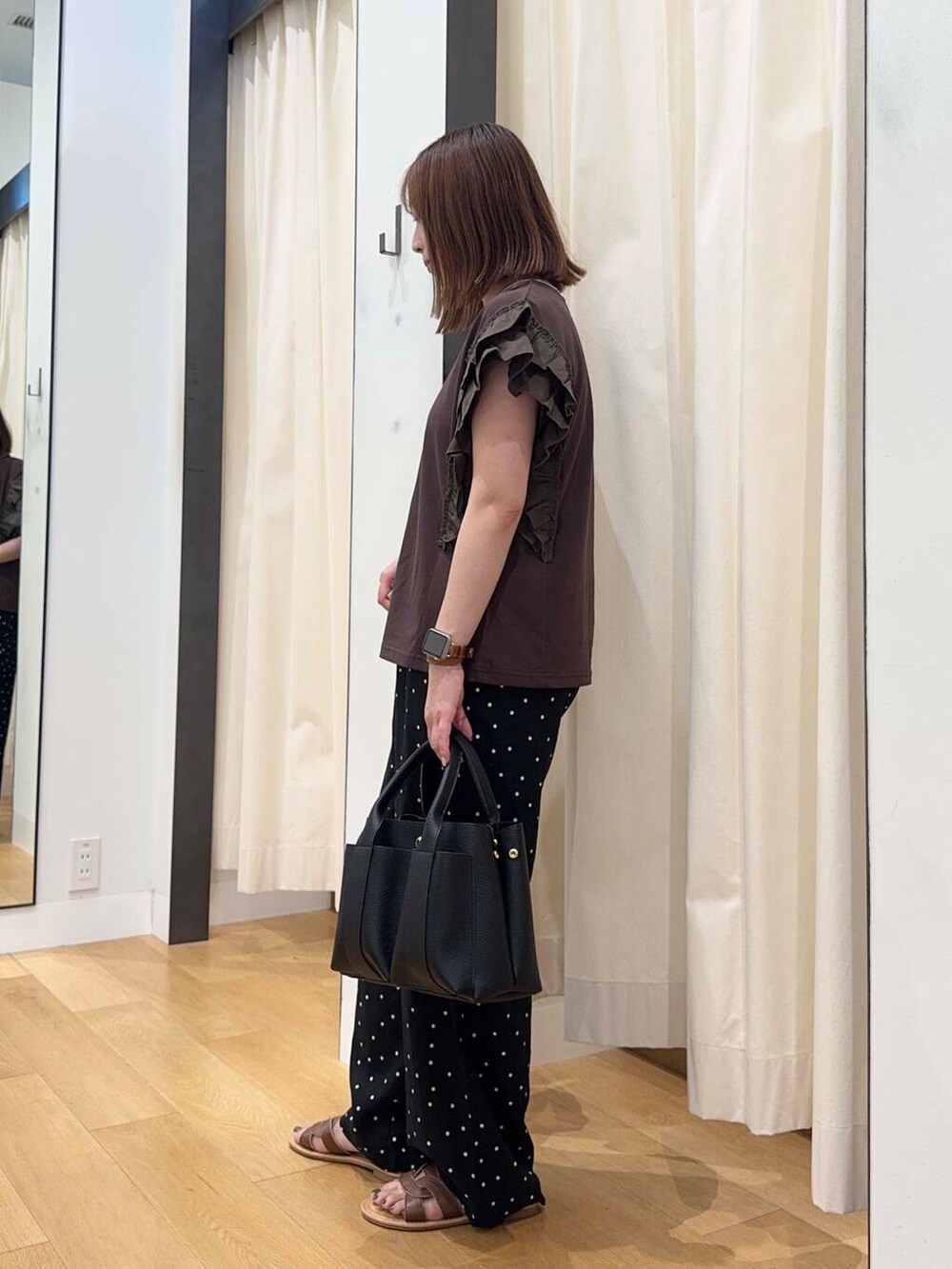 ブラック系のトートバッグ、ブラウン系のサンダル、ブラウン系のTシャツ/カットソーを着用したレディースの夏コーディネートの3枚目の写真