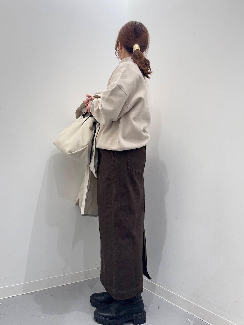 ホワイト系のショルダーバッグ、ブラック系のブーツ、ベージュ系のその他アウターを着用したレディースの冬コーディネートの3枚目の写真