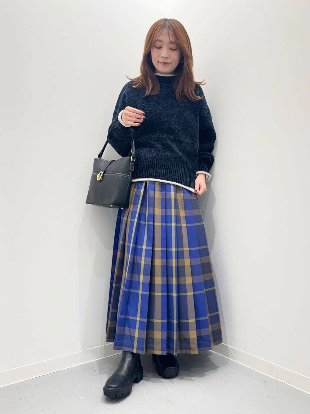 ブラック系のハンドバッグ、ブラック系のブーツ、ブルー系のスカートを着用したレディースの秋コーディネートの4枚目の写真