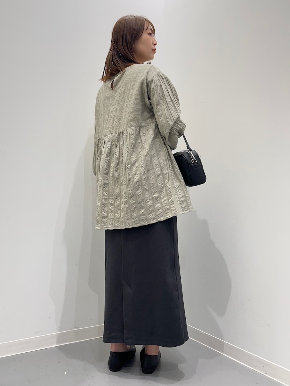 グレー系のシャツ/ブラウス、グレー系のスカート、ブラック系のパンプスを着用したレディースの春コーディネートの5枚目の写真