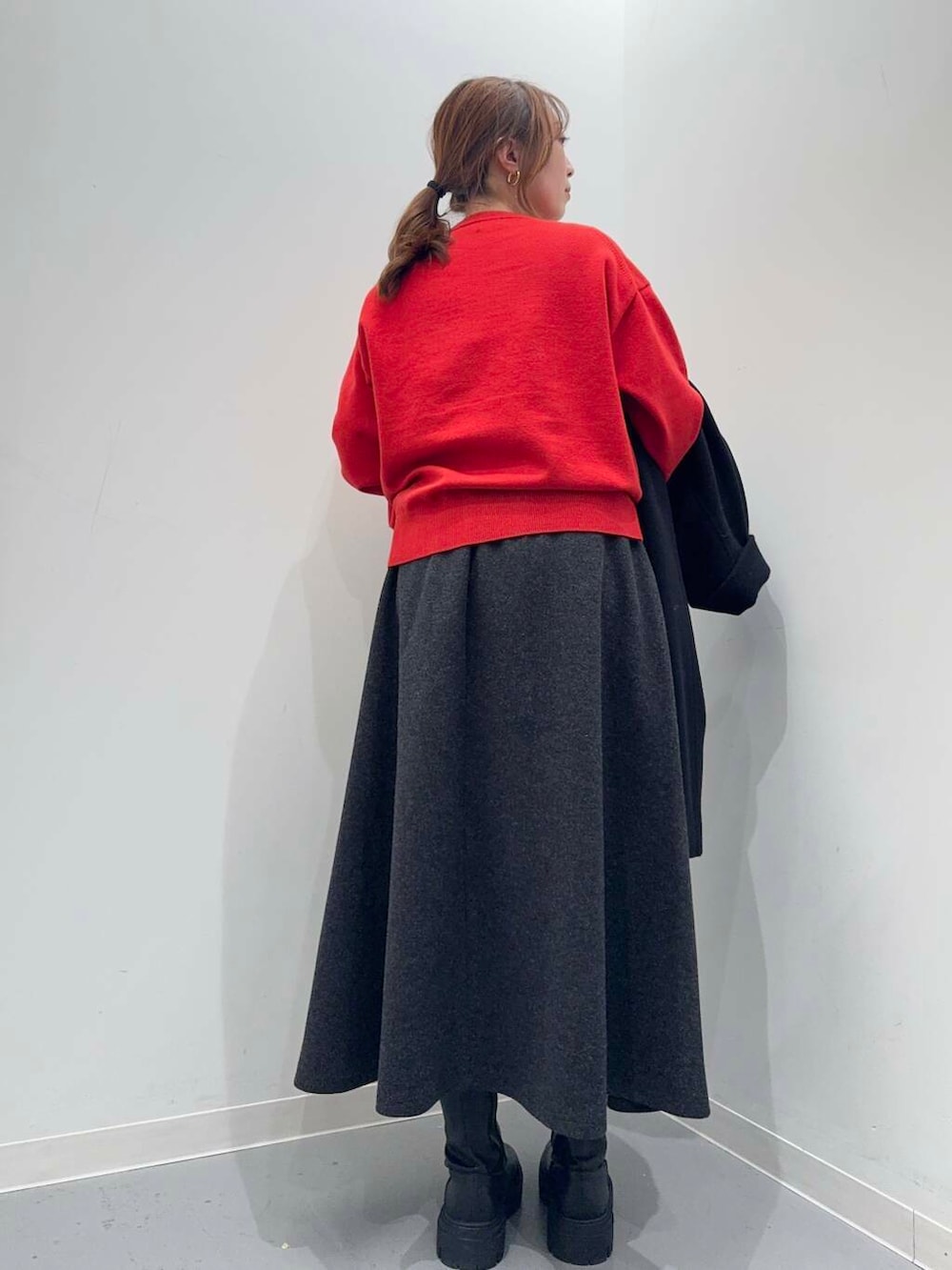 ブラック系のトートバッグ、ブラック系のブーツ、レッド系のニット/セーターを着用したレディースの冬コーディネートの7枚目の写真