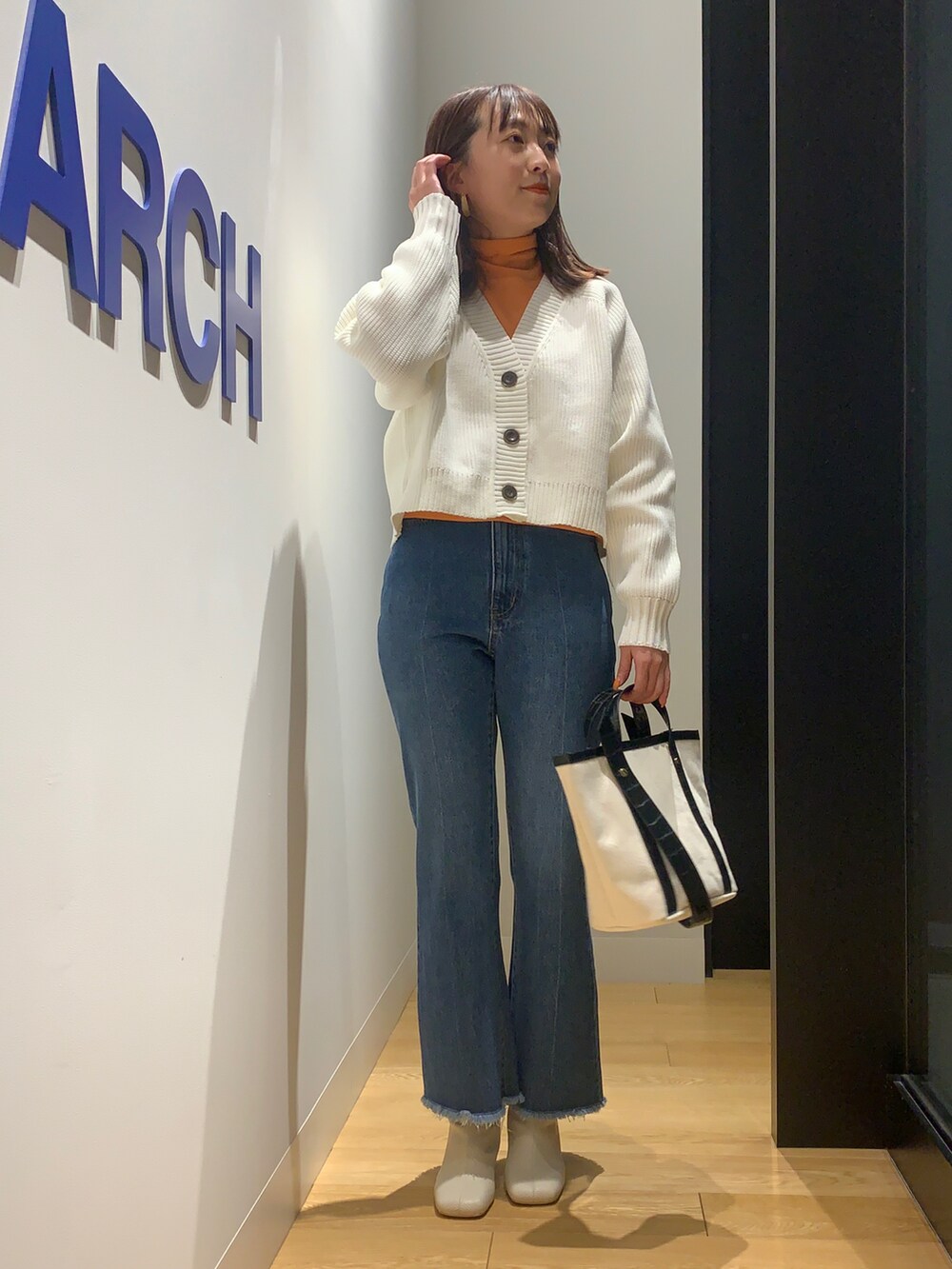 ホワイト系のカーディガン/ボレロ、ブルー系のデニムパンツ、ホワイト系のブーツを着用したレディースの冬コーディネートの3枚目の写真