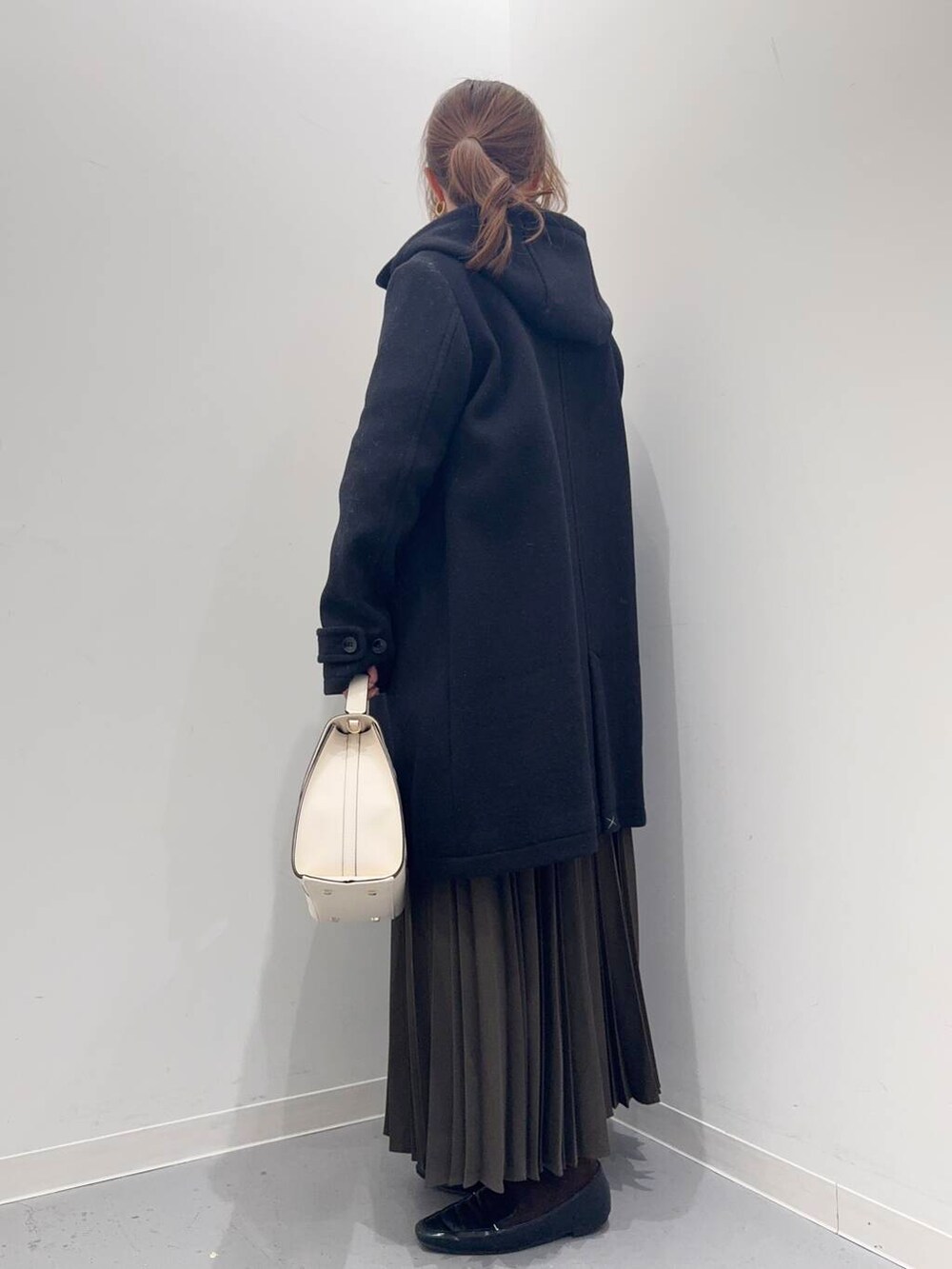 ブラック系のローファー、ブラック系のその他アウター、ホワイト系のハンドバッグを着用したレディースの冬コーディネートの2枚目の写真