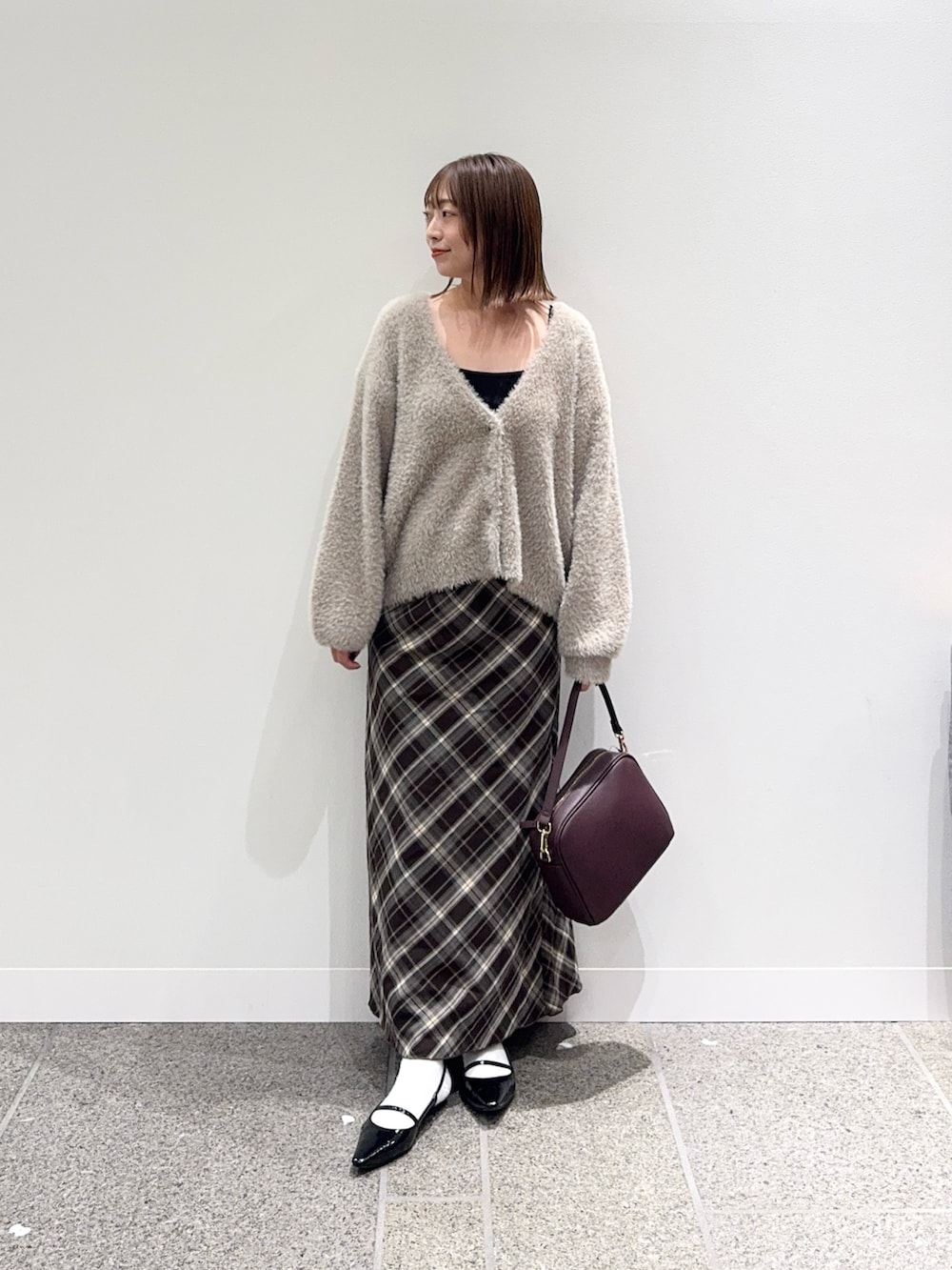 ベージュ系のカーディガン/ボレロ、ブラウン系のスカート、レッド系のショルダーバッグを着用したレディースの秋コーディネートの6枚目の写真