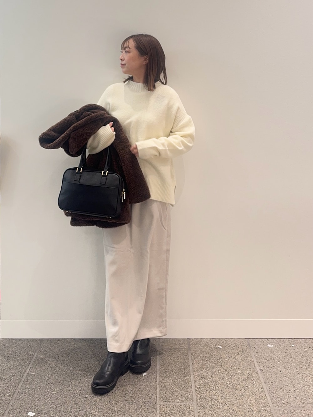 ブラウン系のその他アウター、ホワイト系のニット/セーター、ブラック系のボストンバッグを着用したレディースの冬コーディネートの4枚目の写真