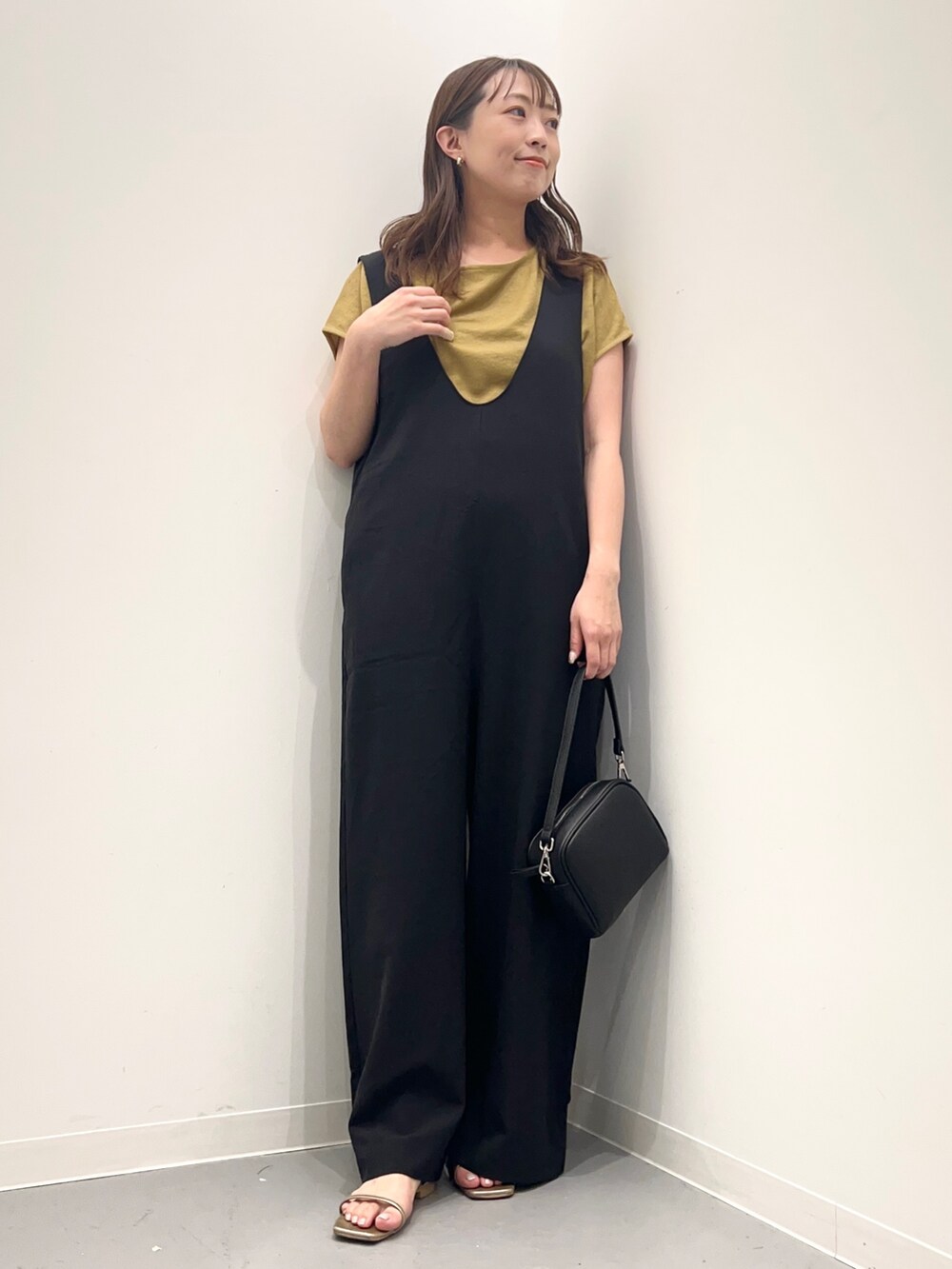 ブラック系のサロペット/オーバーオール、ゴールド系のサンダル、ブラック系のショルダーバッグを着用したレディースの夏コーディネートの3枚目の写真