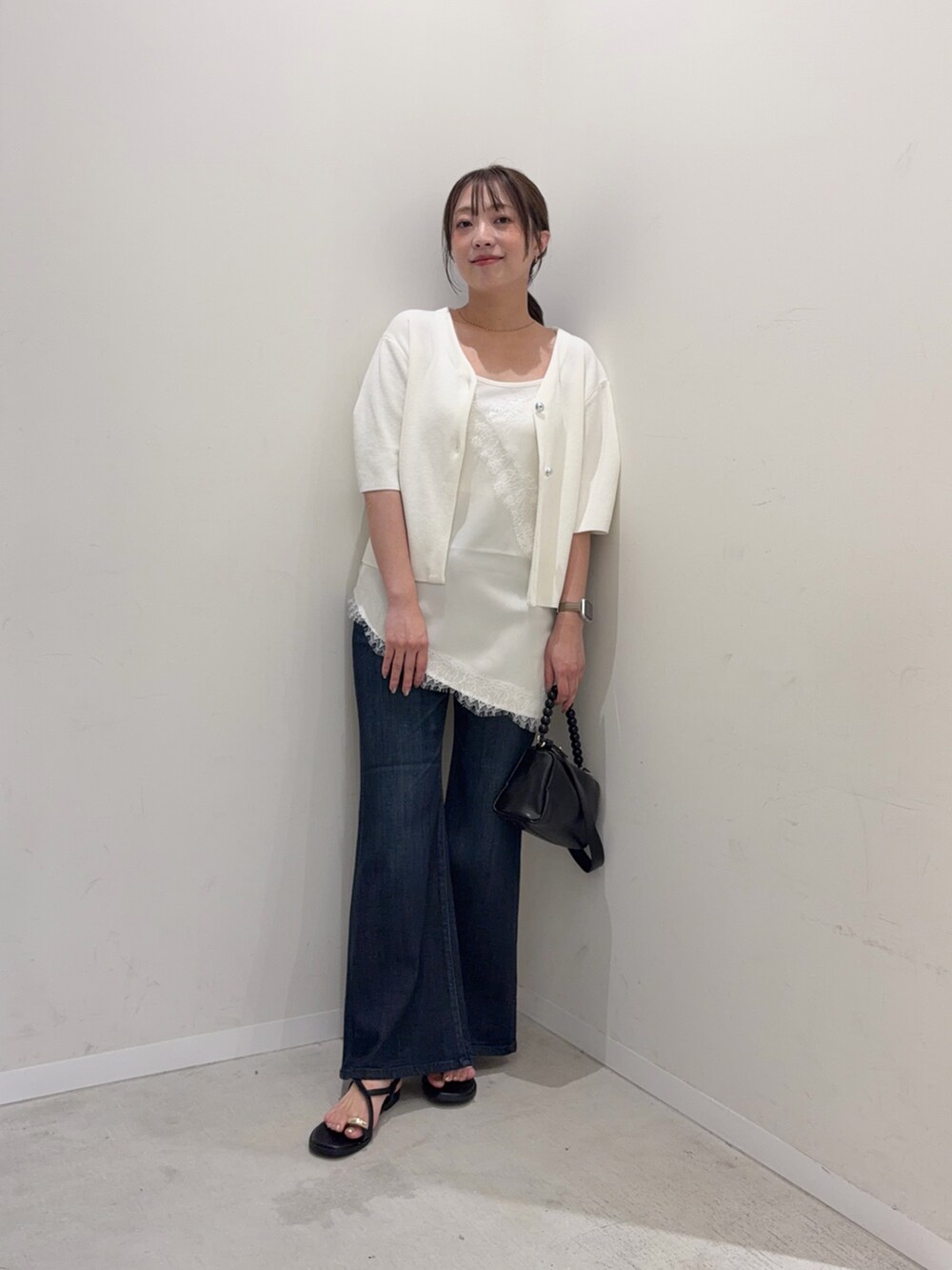 ホワイト系のカーディガン/ボレロ、ホワイト系のキャミソール、ブルー系のデニムパンツを着用したレディースの夏コーディネートの6枚目の写真