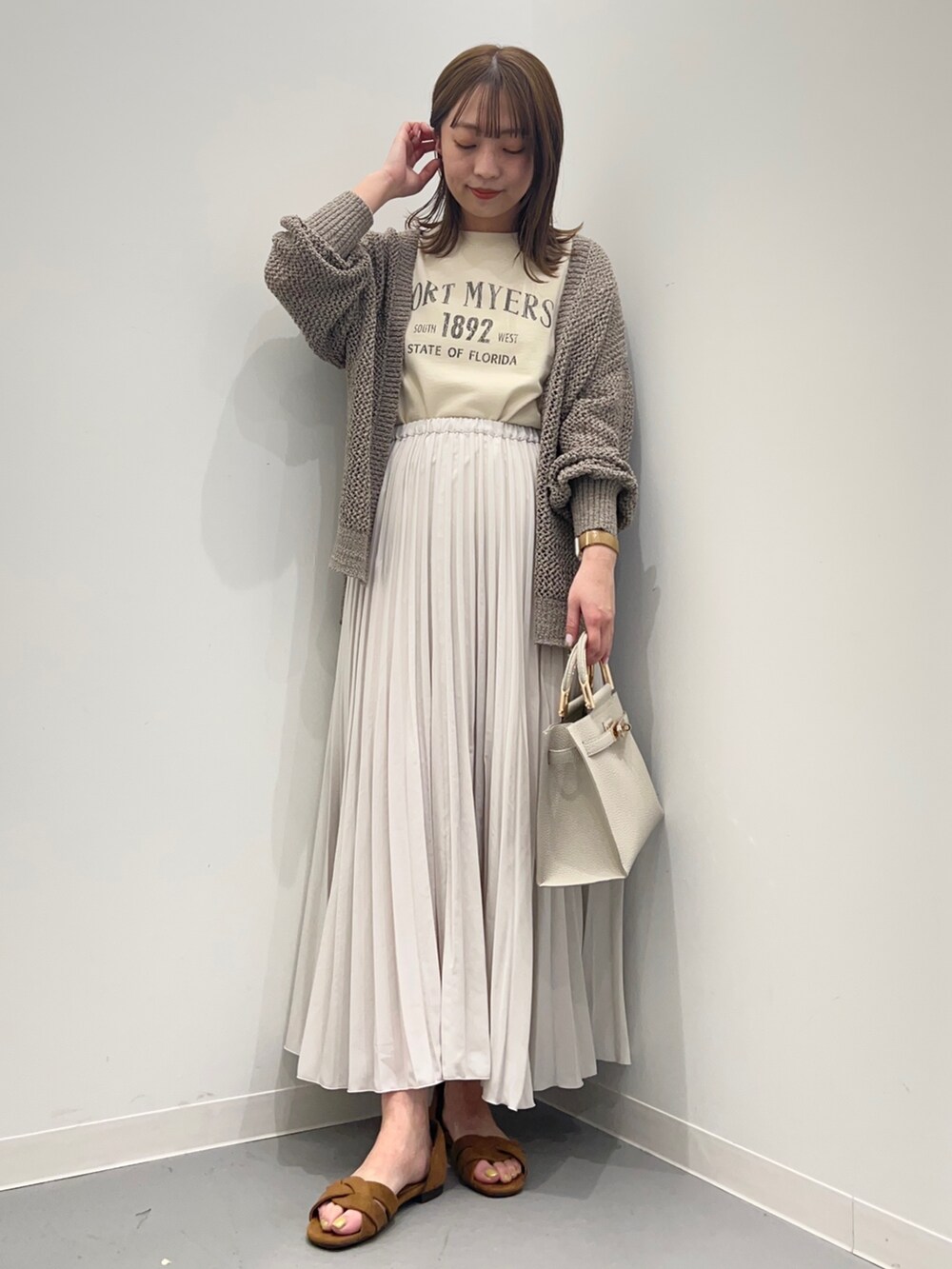 ベージュ系のTシャツ/カットソー、ホワイト系のスカート、グリーン系のカーディガン/ボレロを着用したレディースの春コーディネートの2枚目の写真