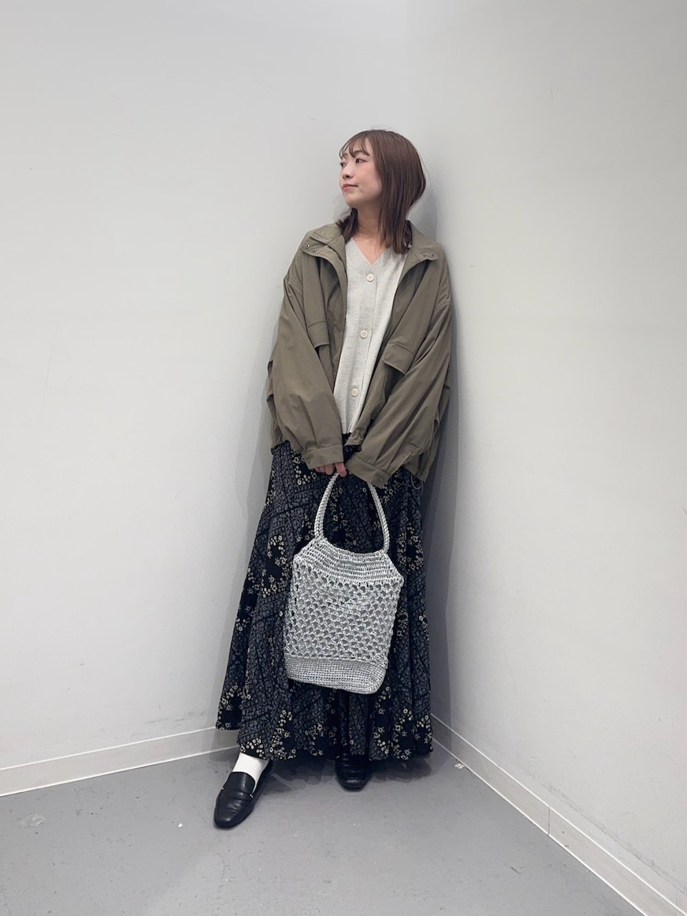 ベージュ系のカーディガン/ボレロ、グリーン系のブルゾン、ブラック系のスカートを着用したレディースの春コーディネートの2枚目の写真