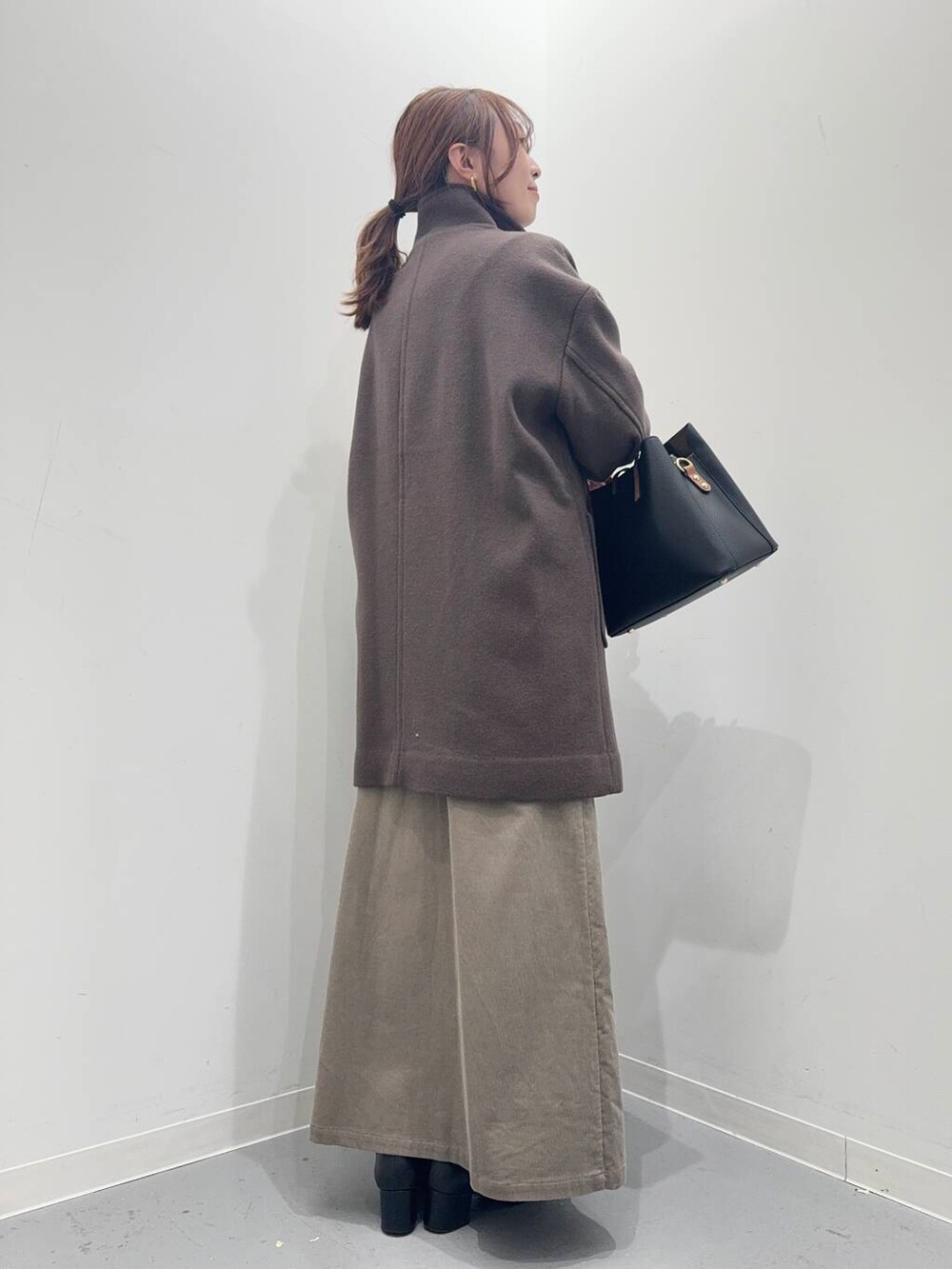 ブラック系のブーツ、ブラック系のトートバッグ、ブラウン系のその他アウターを着用したレディースの冬コーディネートの3枚目の写真