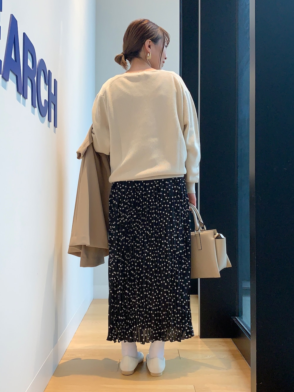 ホワイト系のニット/セーター、ブラック系のスカート、ベージュ系のその他アウターを着用したレディースの春コーディネートの4枚目の写真
