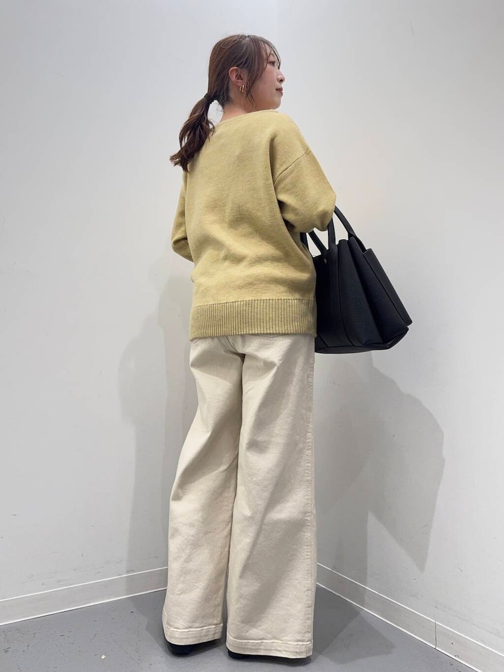 ブラック系のローファー、ブラック系のトートバッグ、イエロー系のニット/セーターを着用したレディースの冬コーディネートの3枚目の写真