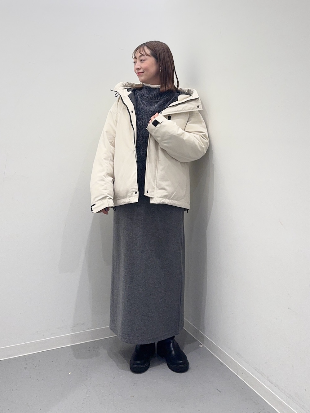 ホワイト系のダウンジャケット/コート、グレー系のニット/セーター、グレー系のスカートを着用したレディースの冬コーディネートの2枚目の写真