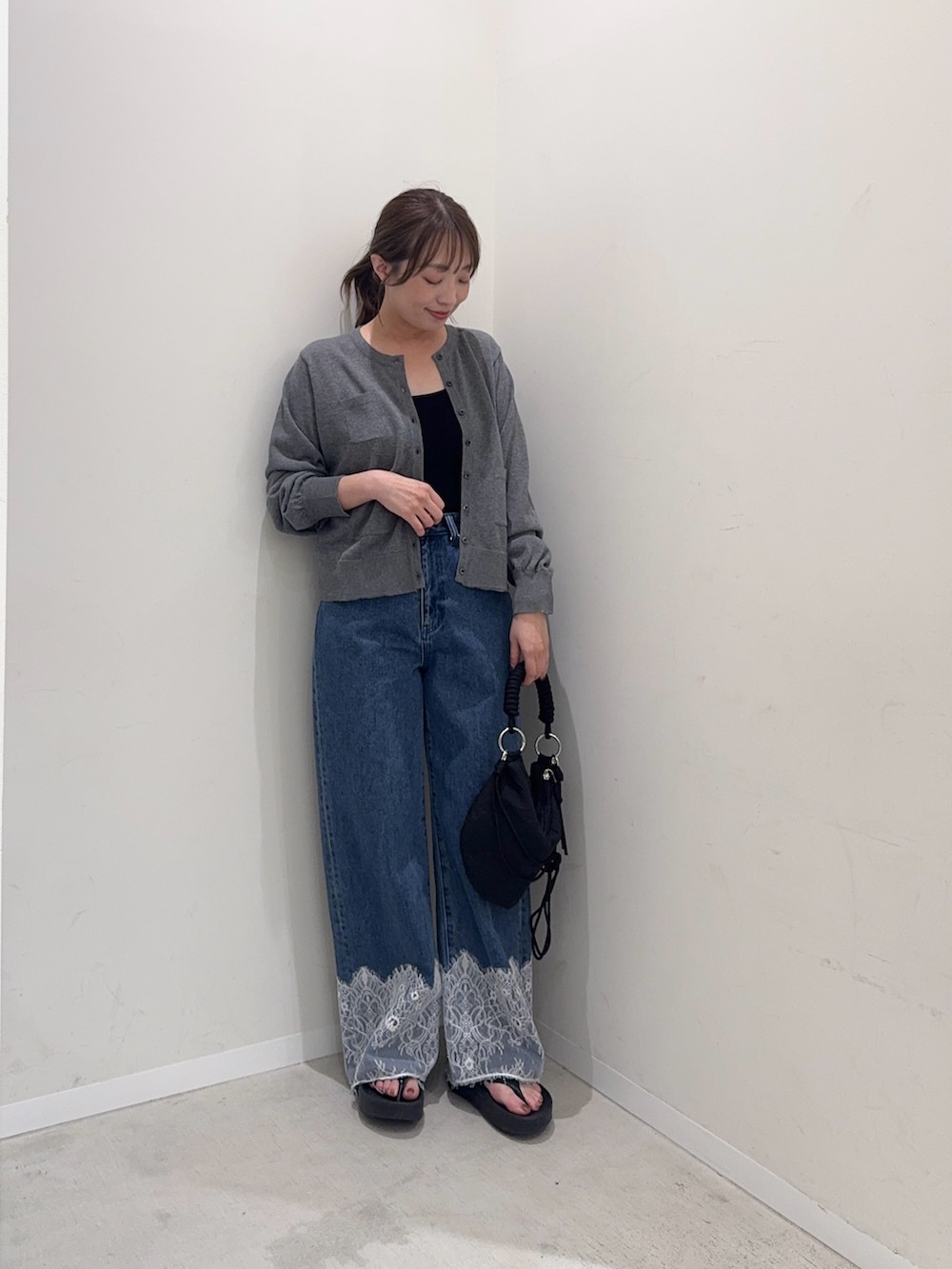 グレー系のカーディガン/ボレロ、ブルー系のデニムパンツ、ブラック系のハンドバッグを着用したレディースの夏コーディネートの2枚目の写真