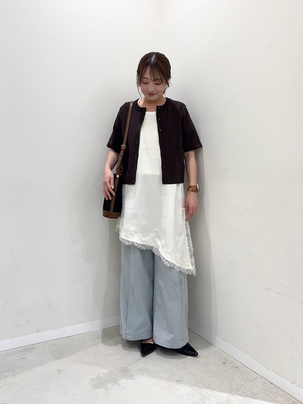 ブラウン系のカーディガン/ボレロ、ホワイト系のキャミソール、ブルー系のデニムパンツを着用したレディースの春コーディネートの2枚目の写真