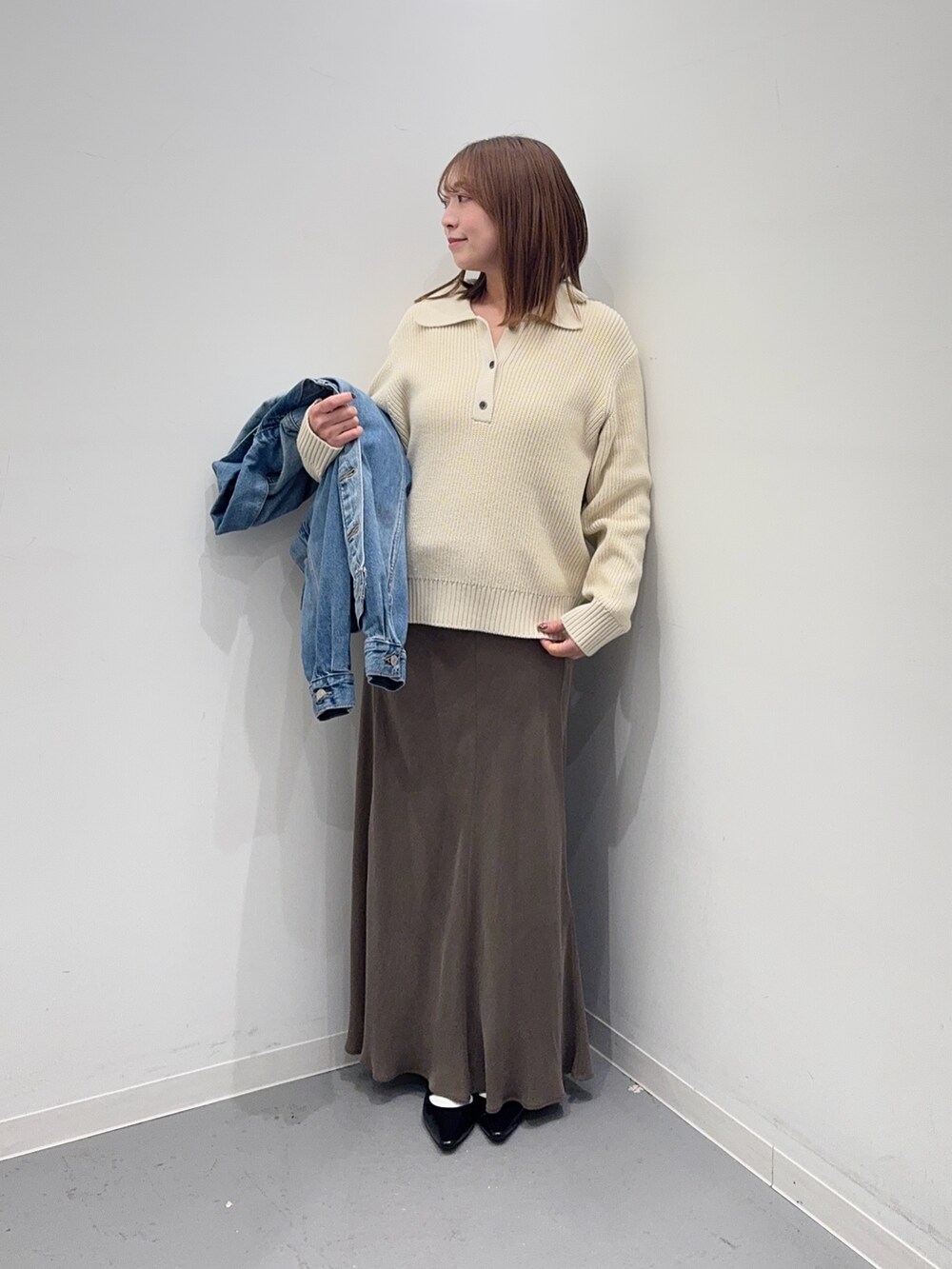 ホワイト系のニット/セーター、ブラウン系のスカート、ブルー系のデニムジャケットを着用したレディースの冬コーディネートの5枚目の写真