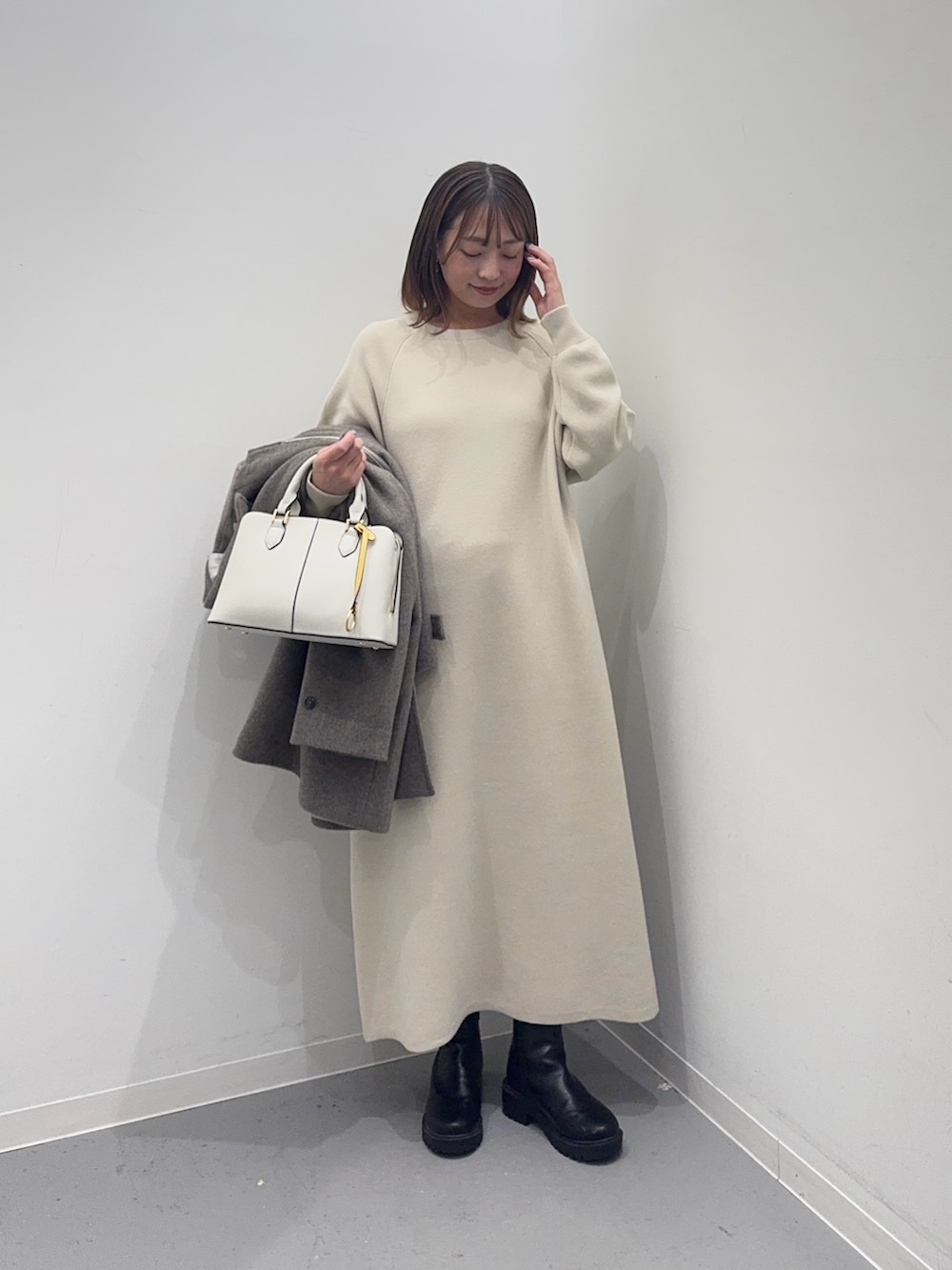 ベージュ系のその他アウター、ベージュ系のワンピース、ホワイト系のハンドバッグを着用したレディースの冬コーディネートの7枚目の写真