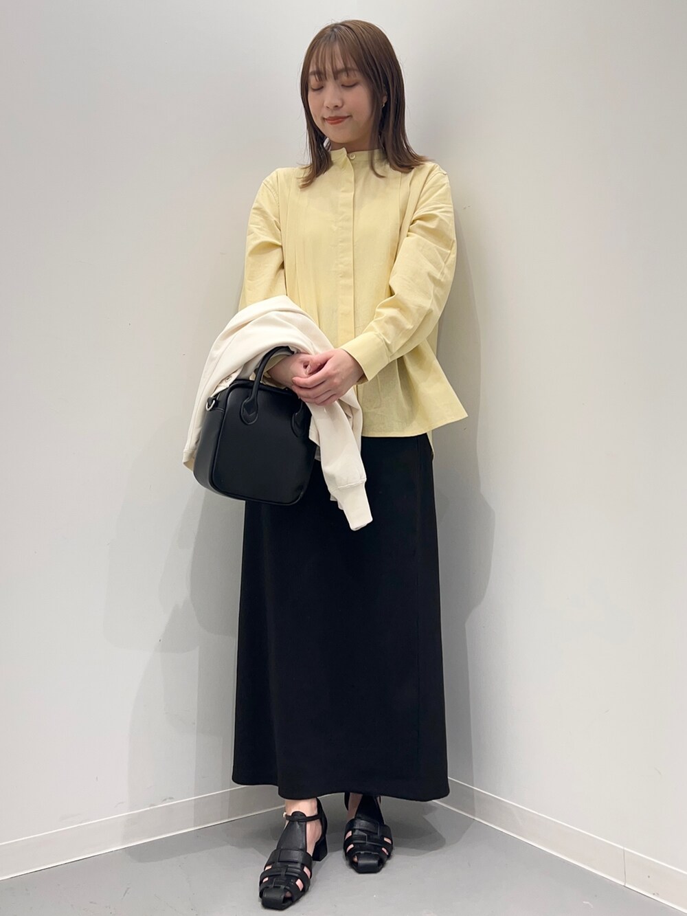 イエロー系のシャツ/ブラウス、ブラック系のスカート、ホワイト系のカーディガン/ボレロを着用したレディースの春コーディネートの8枚目の写真