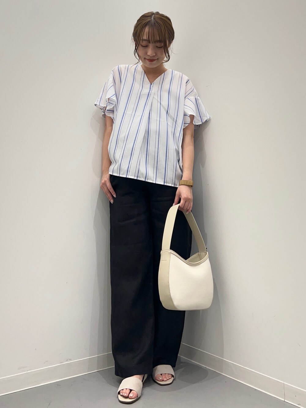 ブルー系のシャツ/ブラウス、ブラック系のその他パンツ、ベージュ系のハンドバッグを着用したレディースの春コーディネートの2枚目の写真