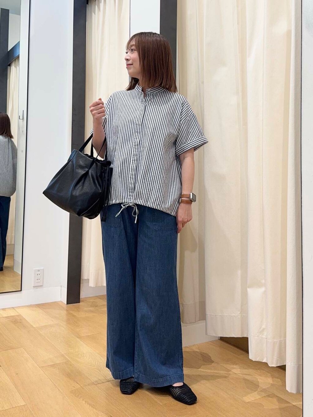 ブラック系のショルダーバッグ、ブルー系のデニムパンツ、ブラック系のバレエシューズを着用したレディースの夏コーディネートの2枚目の写真