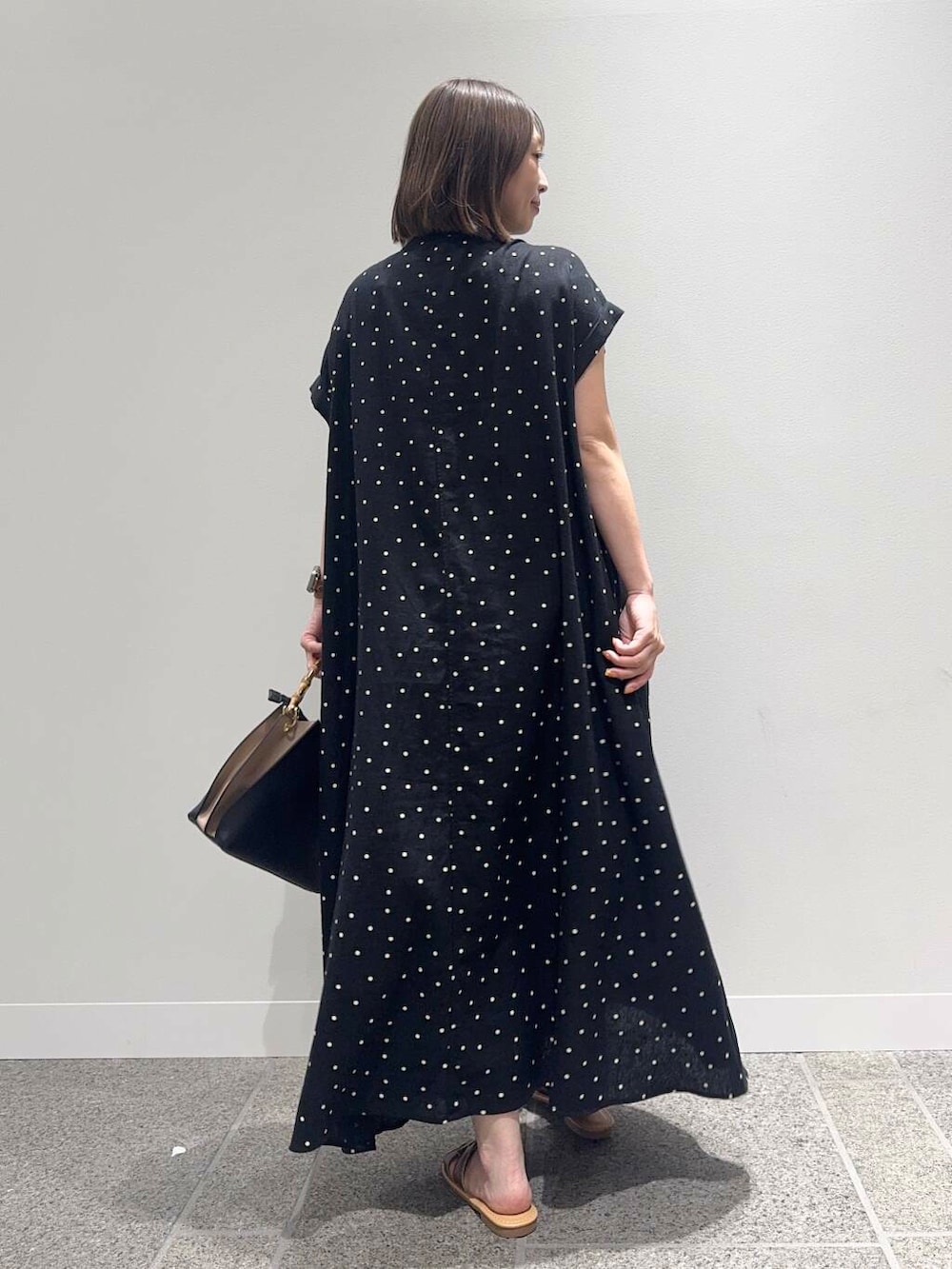 ブラウン系のサンダル、ブラック系のハンドバッグ、ブラック系のワンピースを着用したレディースの夏コーディネートの4枚目の写真