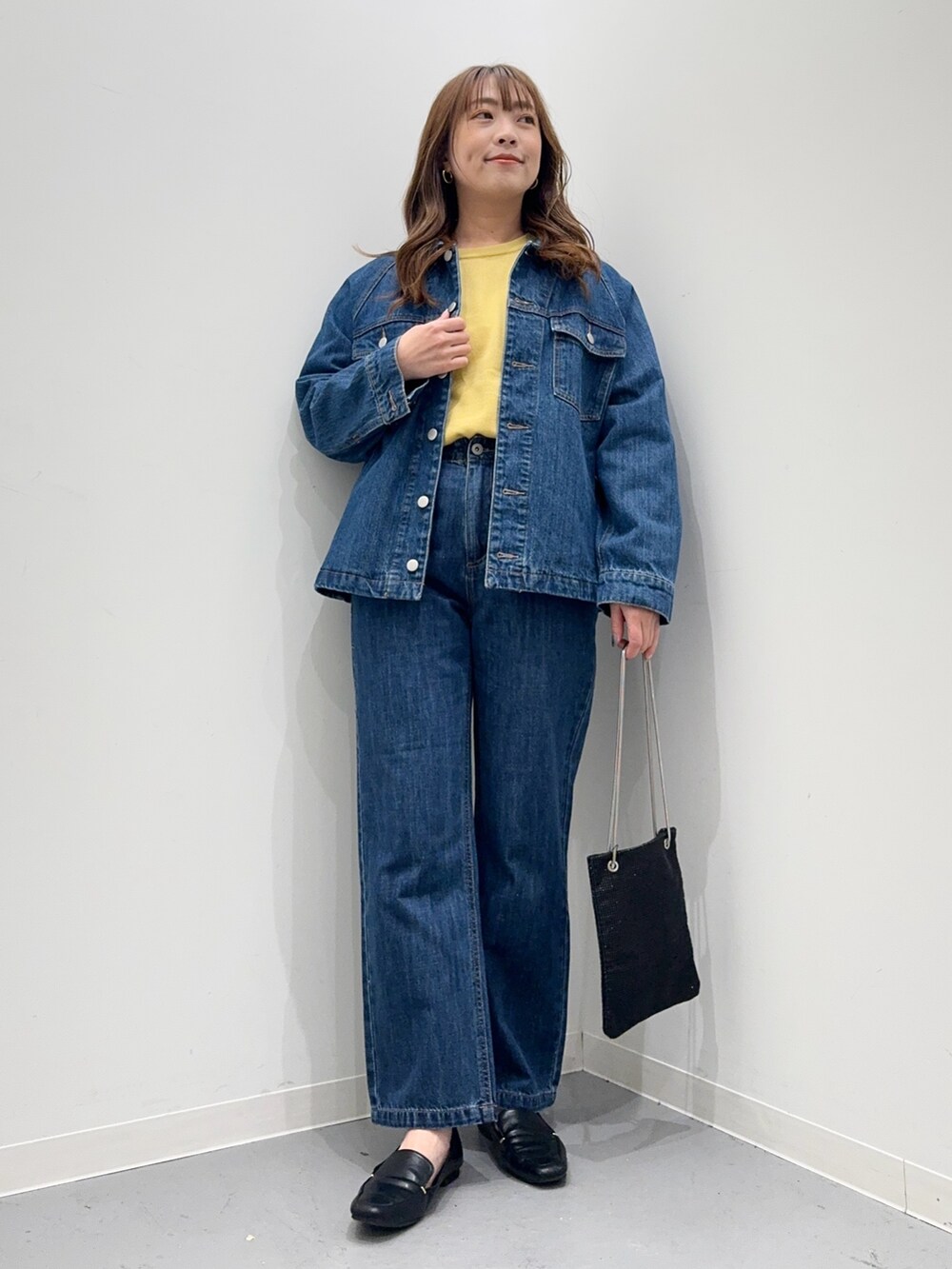 ブルー系のカバーオール、ブルー系のデニムパンツ、イエロー系のニット/セーターを着用したレディースの春コーディネートの2枚目の写真