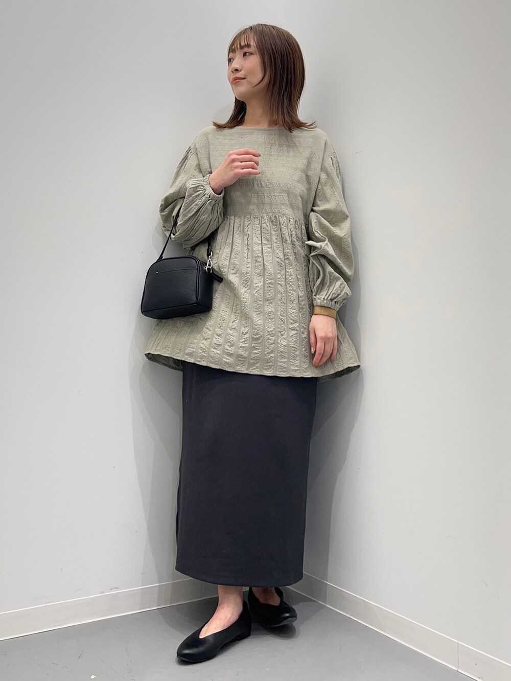 グレー系のシャツ/ブラウス、グレー系のスカート、ブラック系のパンプスを着用したレディースの春コーディネートの2枚目の写真