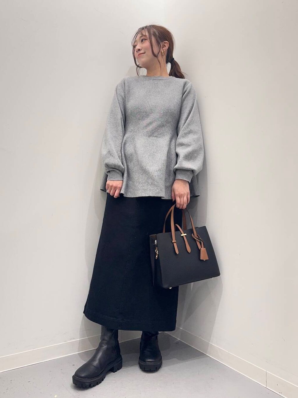 ブラック系のトートバッグ、ブラック系のブーツ、グレー系のニット/セーターを着用したレディースの冬コーディネートの4枚目の写真
