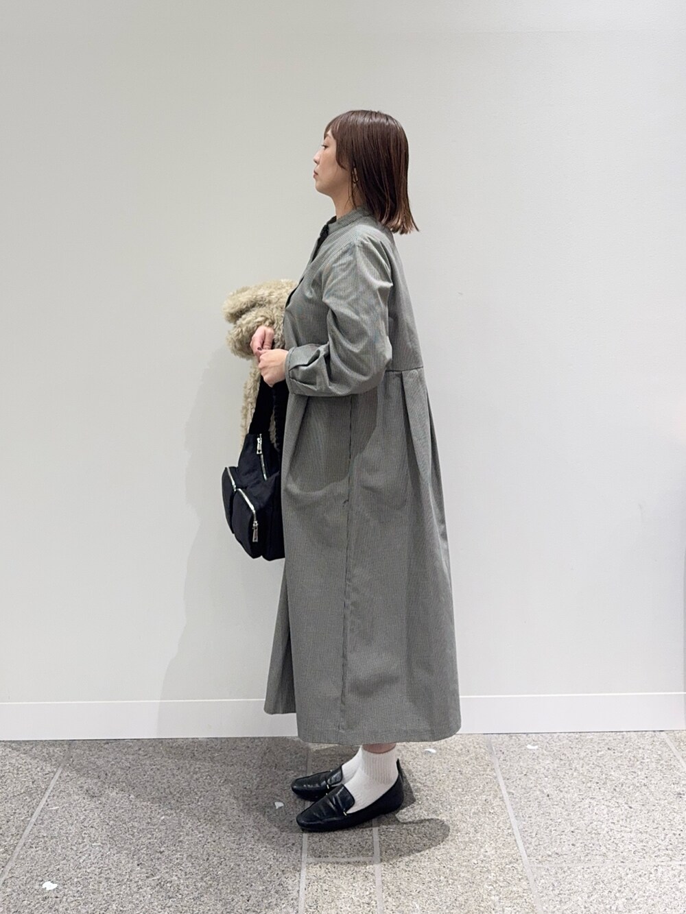 グレー系のワンピース、ベージュ系のその他アウター、ブラック系のショルダーバッグを着用したレディースの秋コーディネートの2枚目の写真