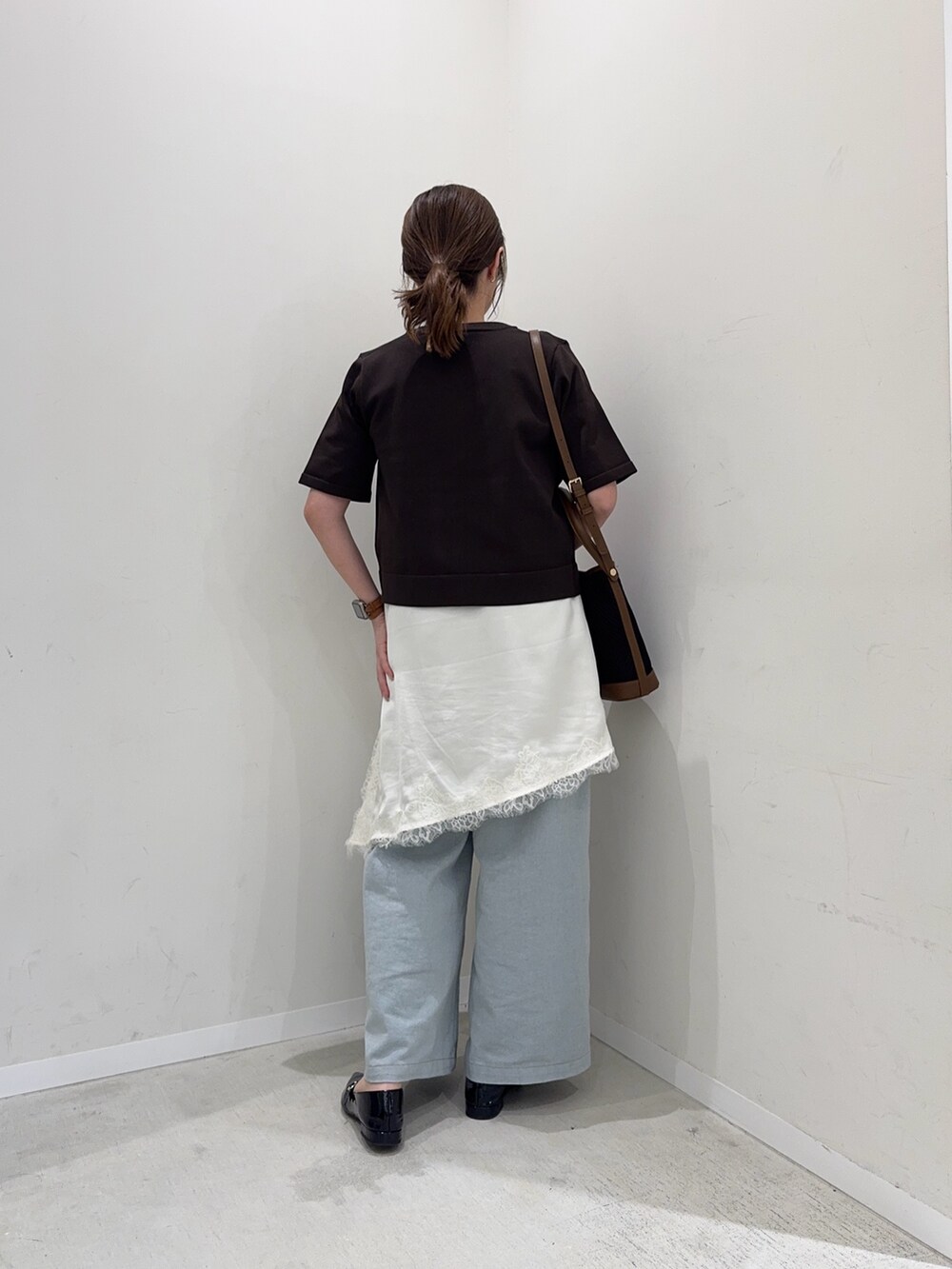 ブラウン系のカーディガン/ボレロ、ホワイト系のキャミソール、ブルー系のデニムパンツを着用したレディースの春コーディネートの4枚目の写真