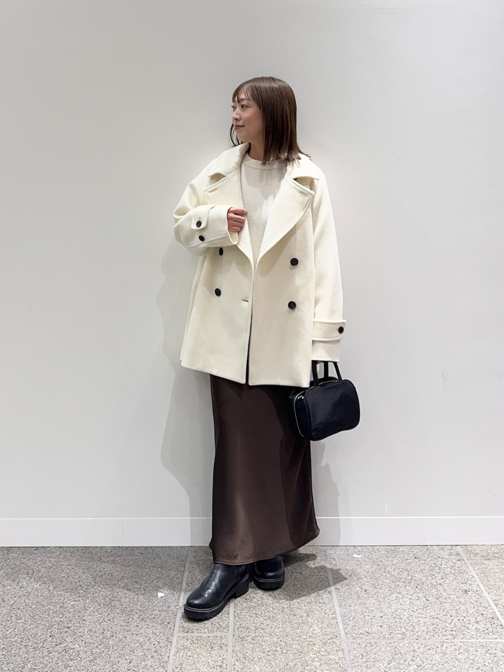 ホワイト系のピーコート、ホワイト系のニット/セーター、ブラック系のボストンバッグを着用したレディースの冬コーディネートの4枚目の写真