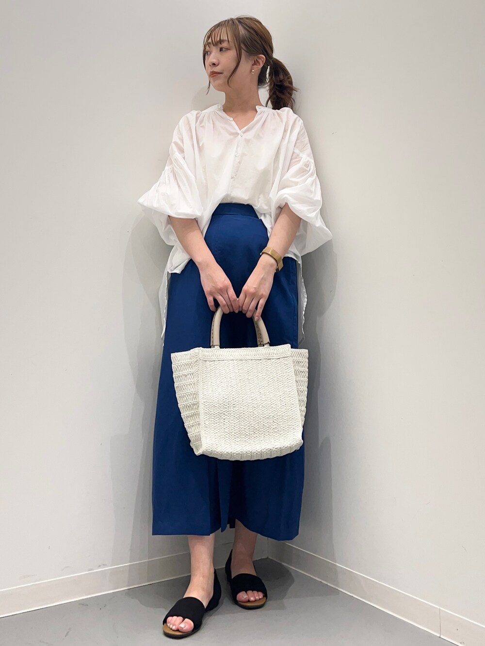 ホワイト系のシャツ/ブラウス、ブルー系のスカート、ベージュ系のトートバッグを着用したレディースの春コーディネートの2枚目の写真