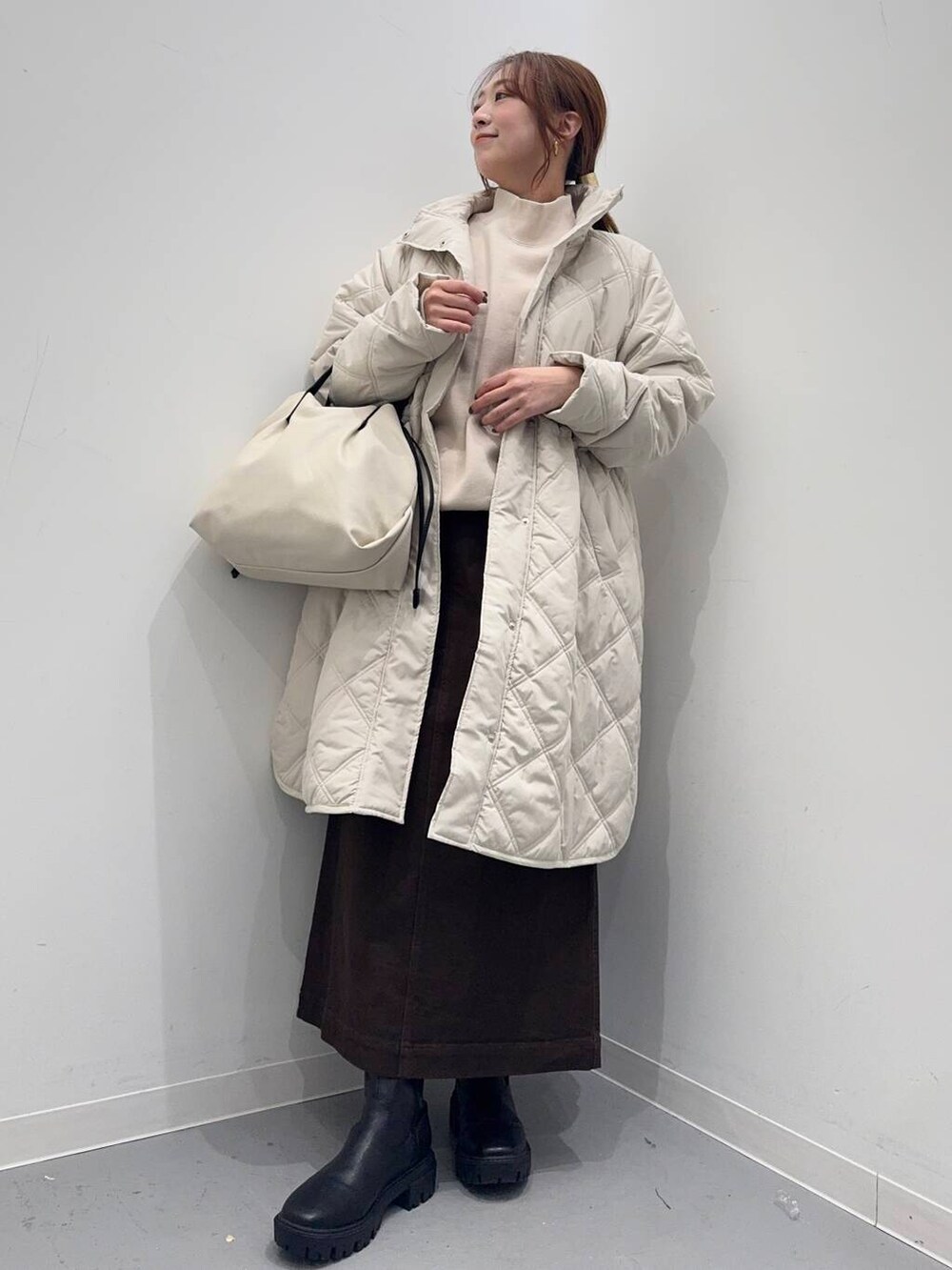 ホワイト系のショルダーバッグ、ブラック系のブーツ、ベージュ系のその他アウターを着用したレディースの冬コーディネートの6枚目の写真