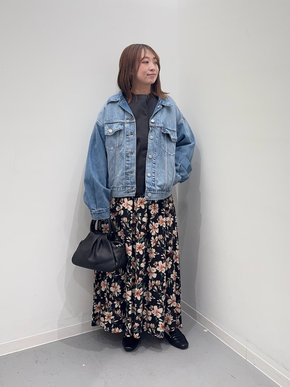 ブルー系のデニムジャケット、グレー系のカーディガン/ボレロ、ブラック系のスカートを着用したレディースの冬コーディネートの2枚目の写真