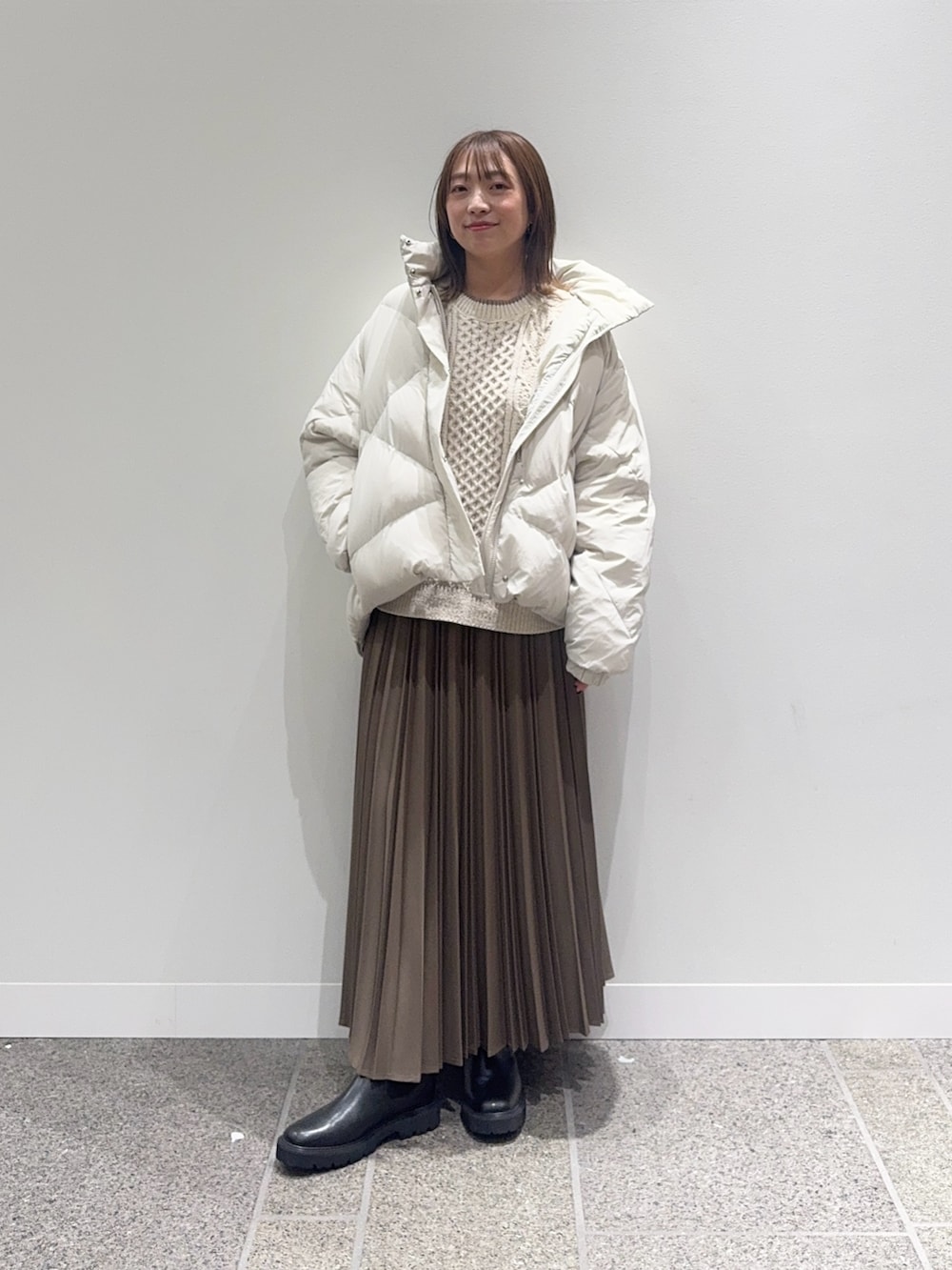ホワイト系のダウンジャケット/コート、ホワイト系のニット/セーター、ベージュ系のスカートを着用したレディースの冬コーディネートの5枚目の写真