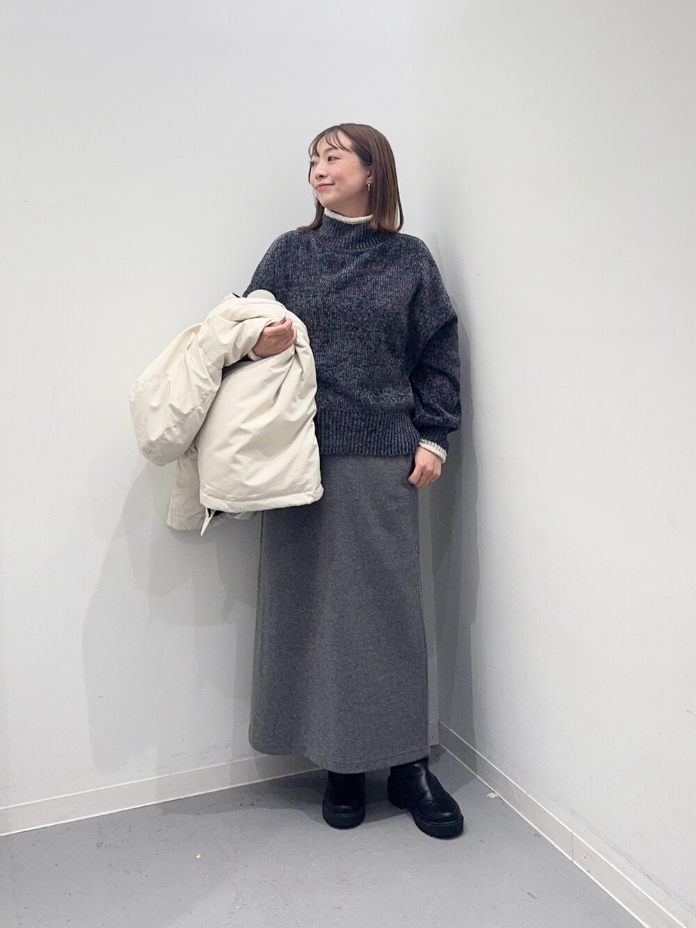 ホワイト系のダウンジャケット/コート、グレー系のニット/セーター、グレー系のスカートを着用したレディースの冬コーディネートの9枚目の写真