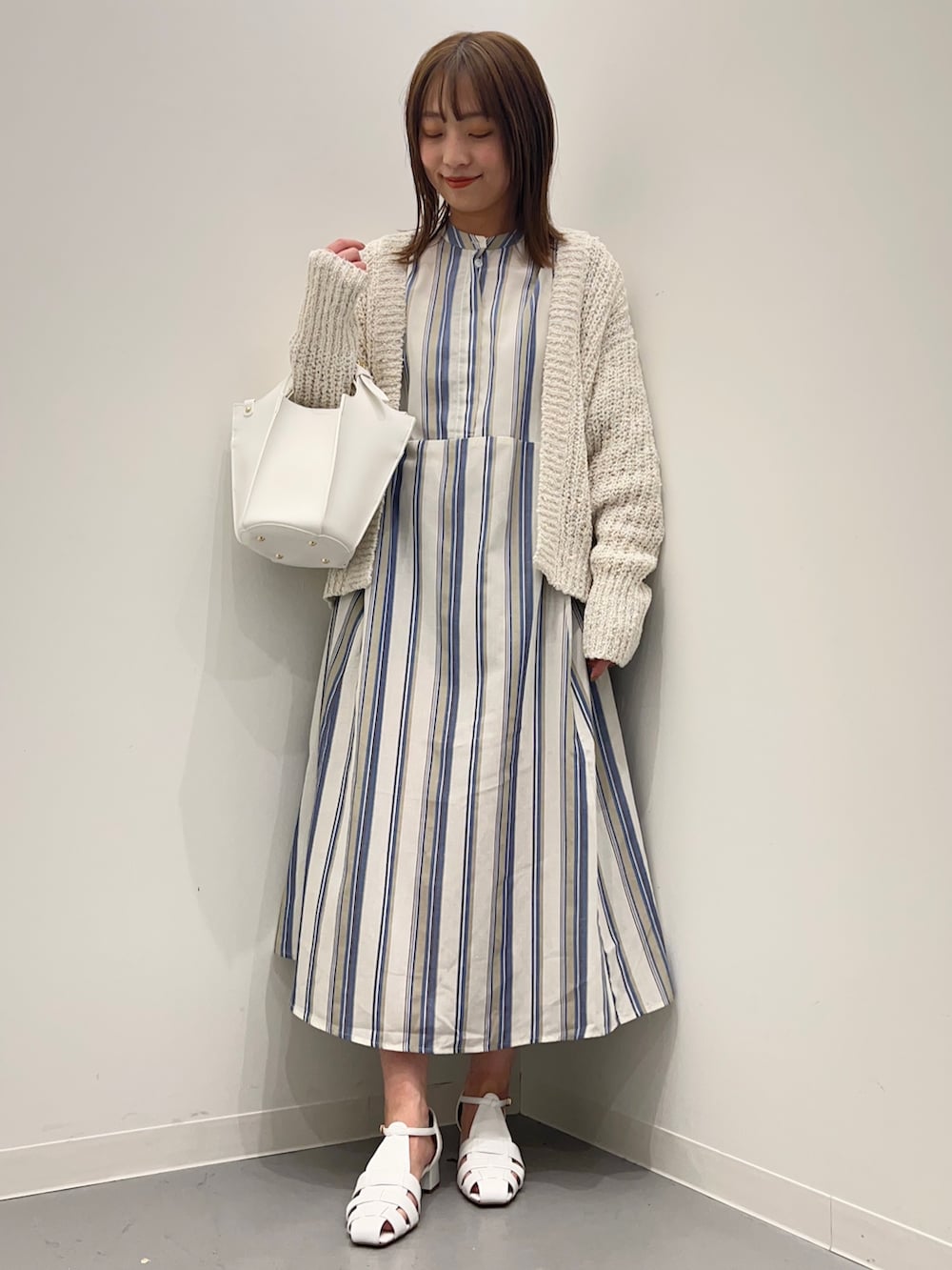 ホワイト系のカーディガン/ボレロ、ホワイト系のサンダル、ブルー系のワンピースを着用したレディースの春コーディネートの2枚目の写真