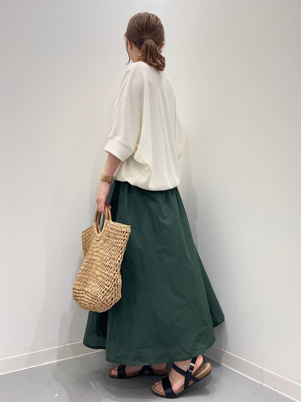 ベージュ系のTシャツ/カットソー、グリーン系のスカート、ブラック系のサンダルを着用したレディースの春コーディネートの4枚目の写真