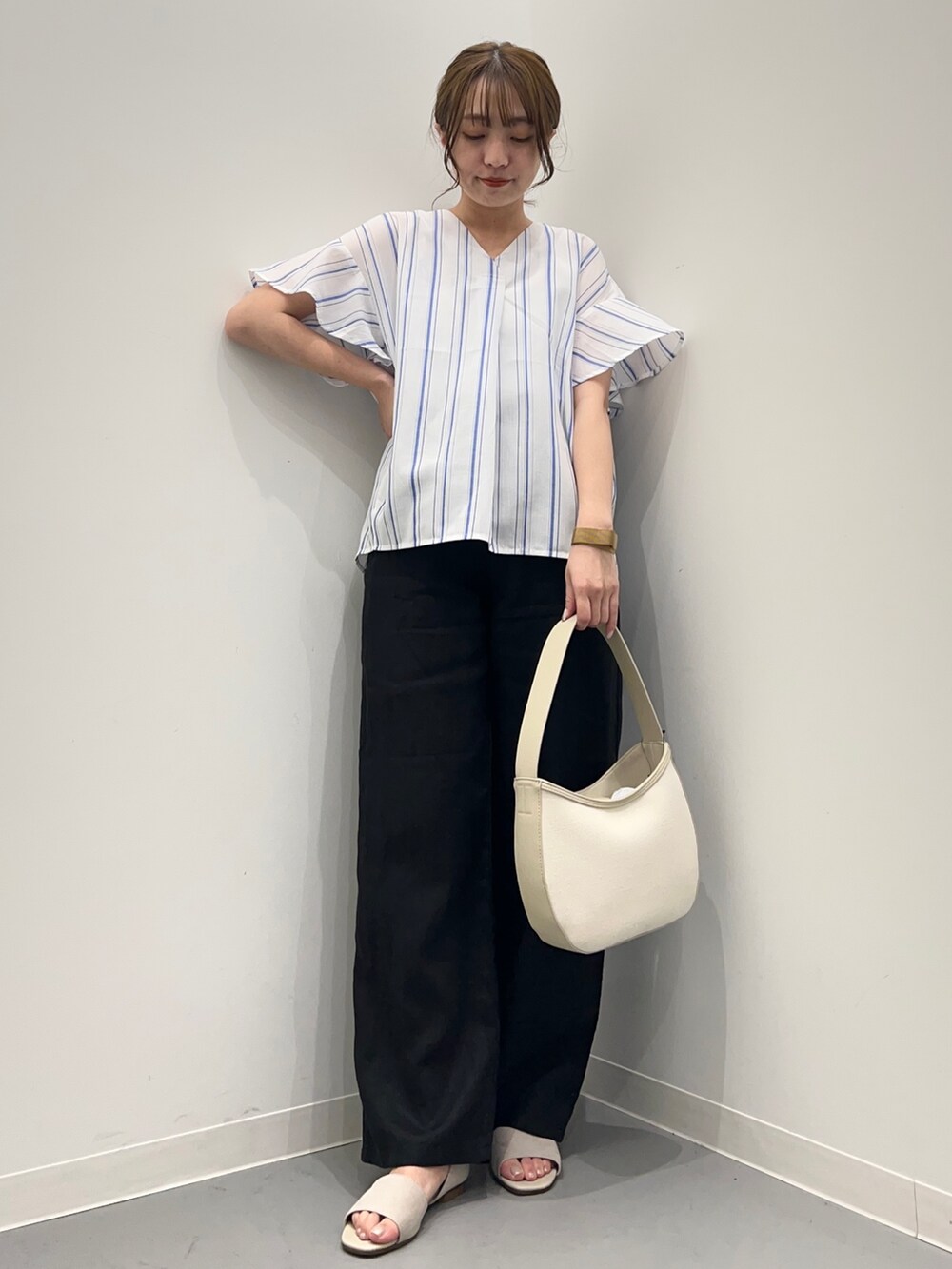 ブルー系のシャツ/ブラウス、ブラック系のその他パンツ、ベージュ系のハンドバッグを着用したレディースの春コーディネートの3枚目の写真