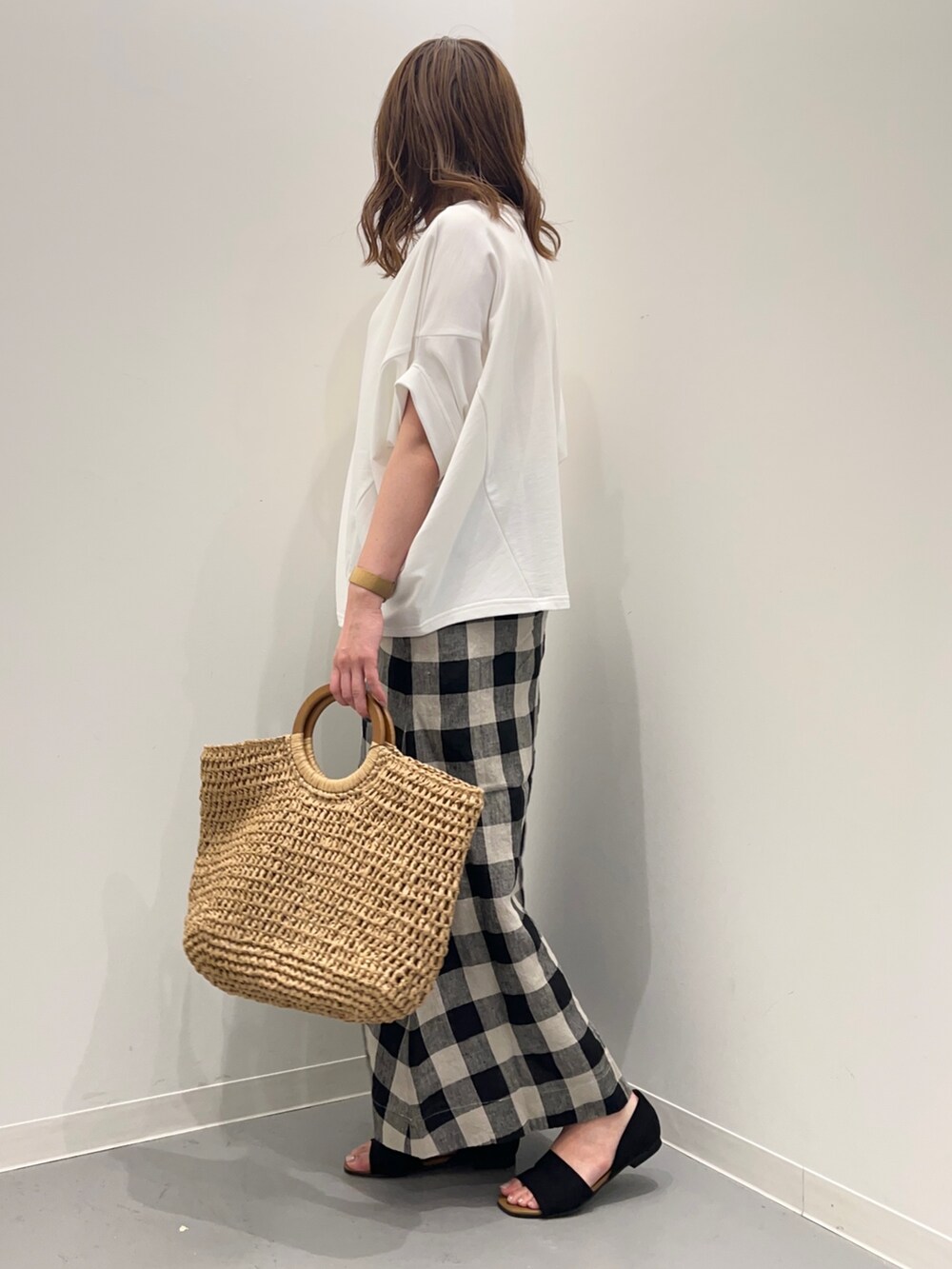 ホワイト系のTシャツ/カットソー、ブラック系のスカート、ベージュ系のかごバッグを着用したレディースの春コーディネートの4枚目の写真