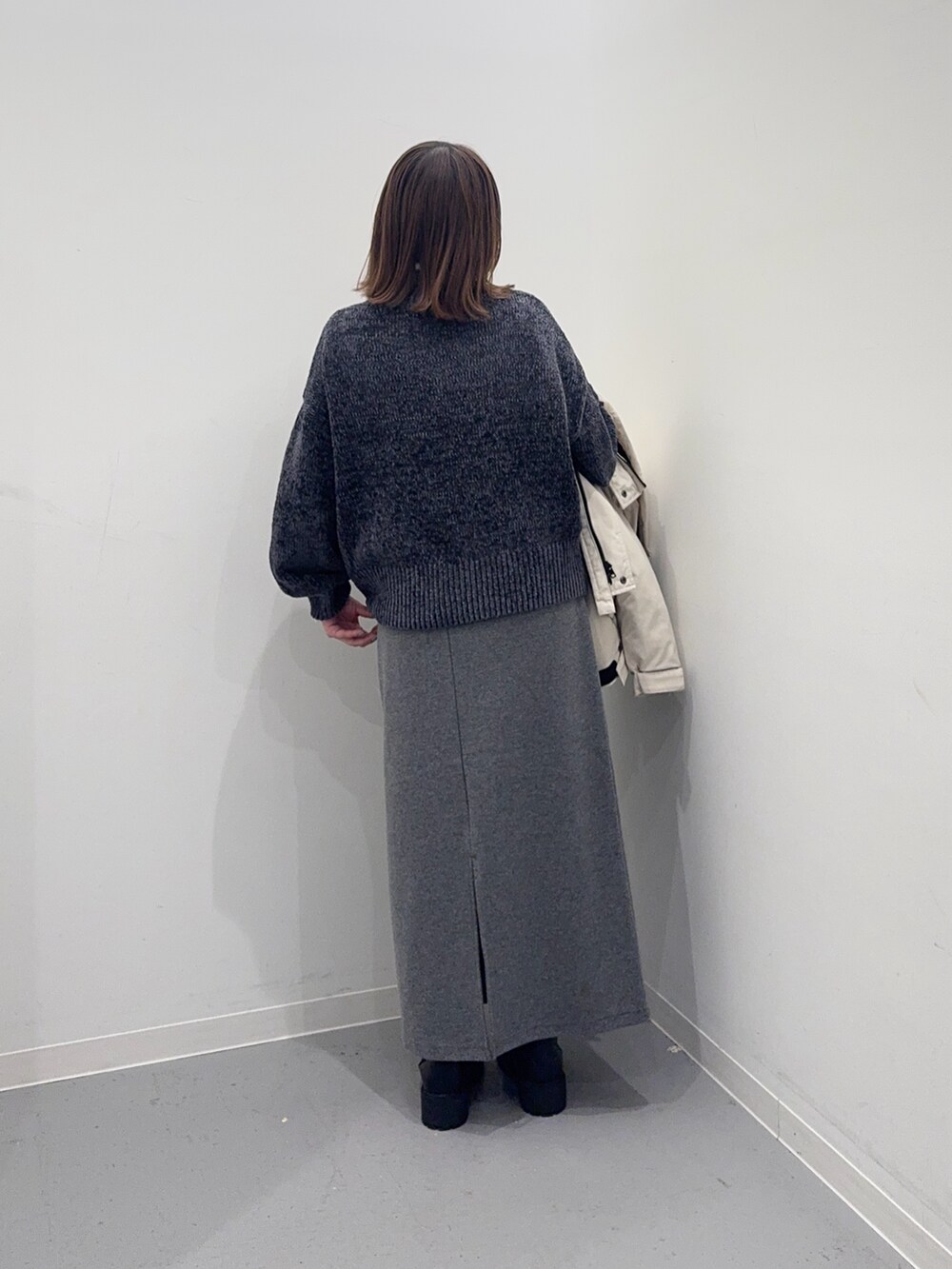 ホワイト系のダウンジャケット/コート、グレー系のニット/セーター、グレー系のスカートを着用したレディースの冬コーディネートの8枚目の写真
