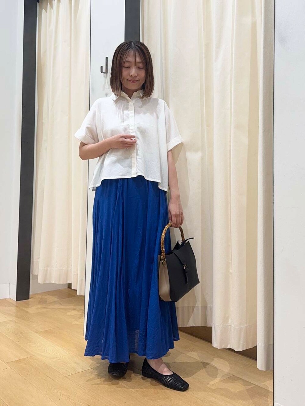 ブラック系のバレエシューズ、ブルー系のスカート、ホワイト系のシャツ/ブラウスを着用したレディースの夏コーディネートの2枚目の写真